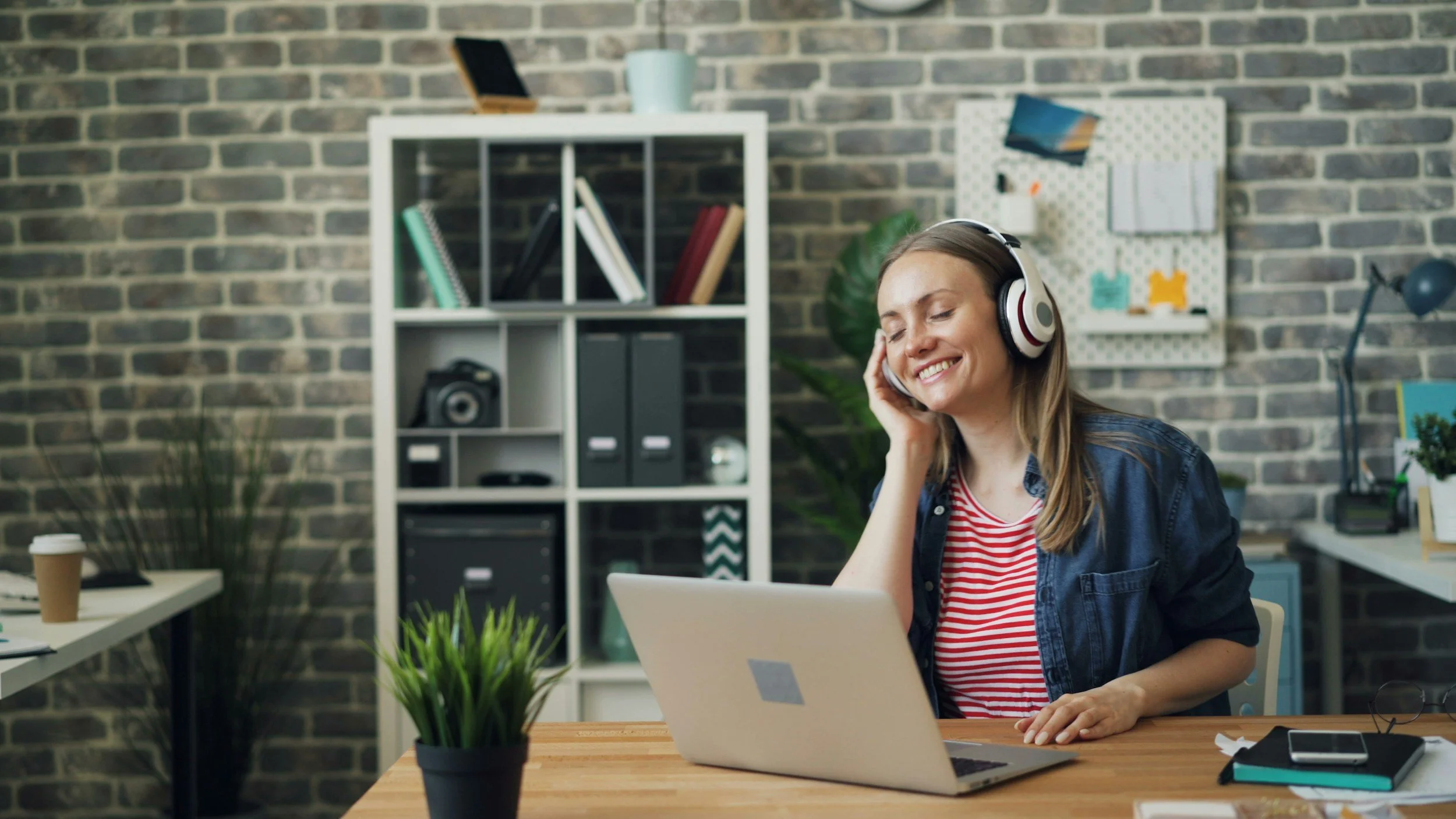 A young woman with headphones smiling and working with her therapist in a virtual therapy session.