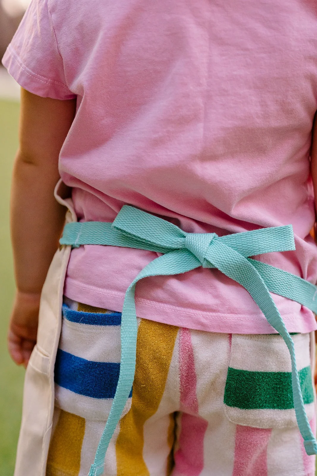 Child wearing a personalized ARTWELL art apron decorated with fabric markers.