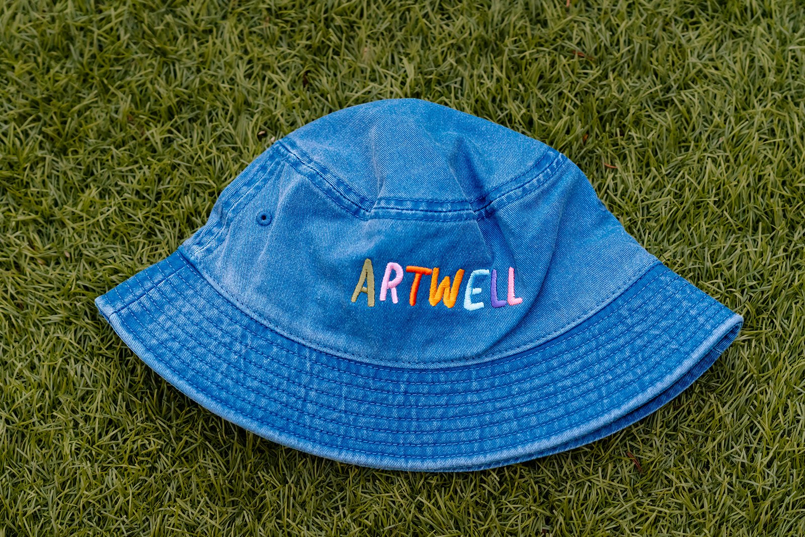 Child wearing the sea blue ARTWELL embroidered bucket hat outdoors.