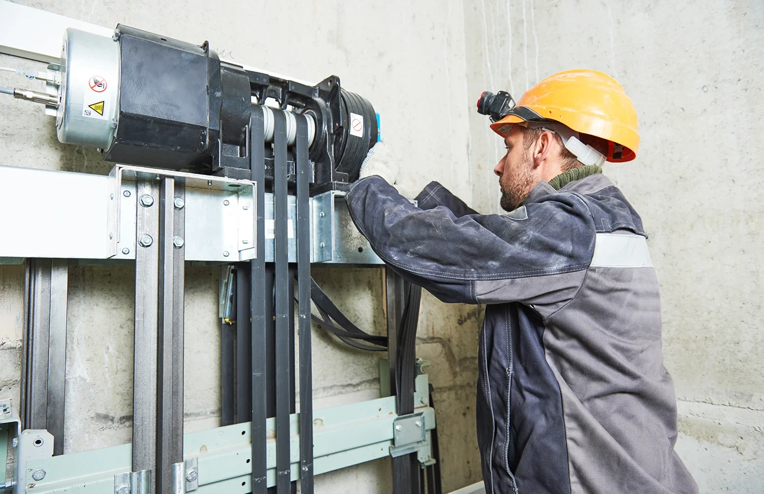 Electrician or technician working on electrical or machinery equipment with a yellow safety helmet.