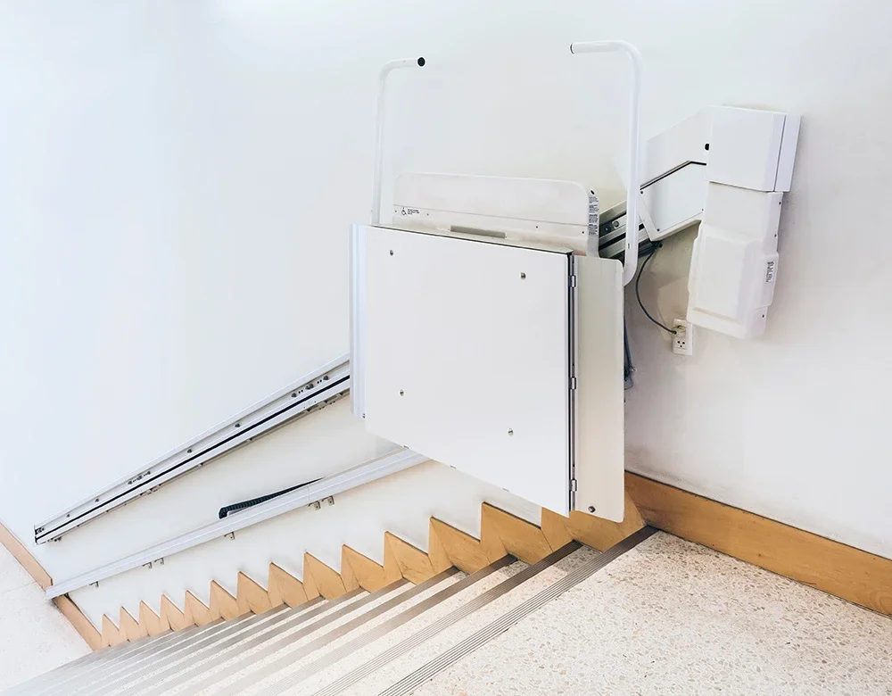 Medical stair lift installed on staircase with wooden steps in a healthcare facility.