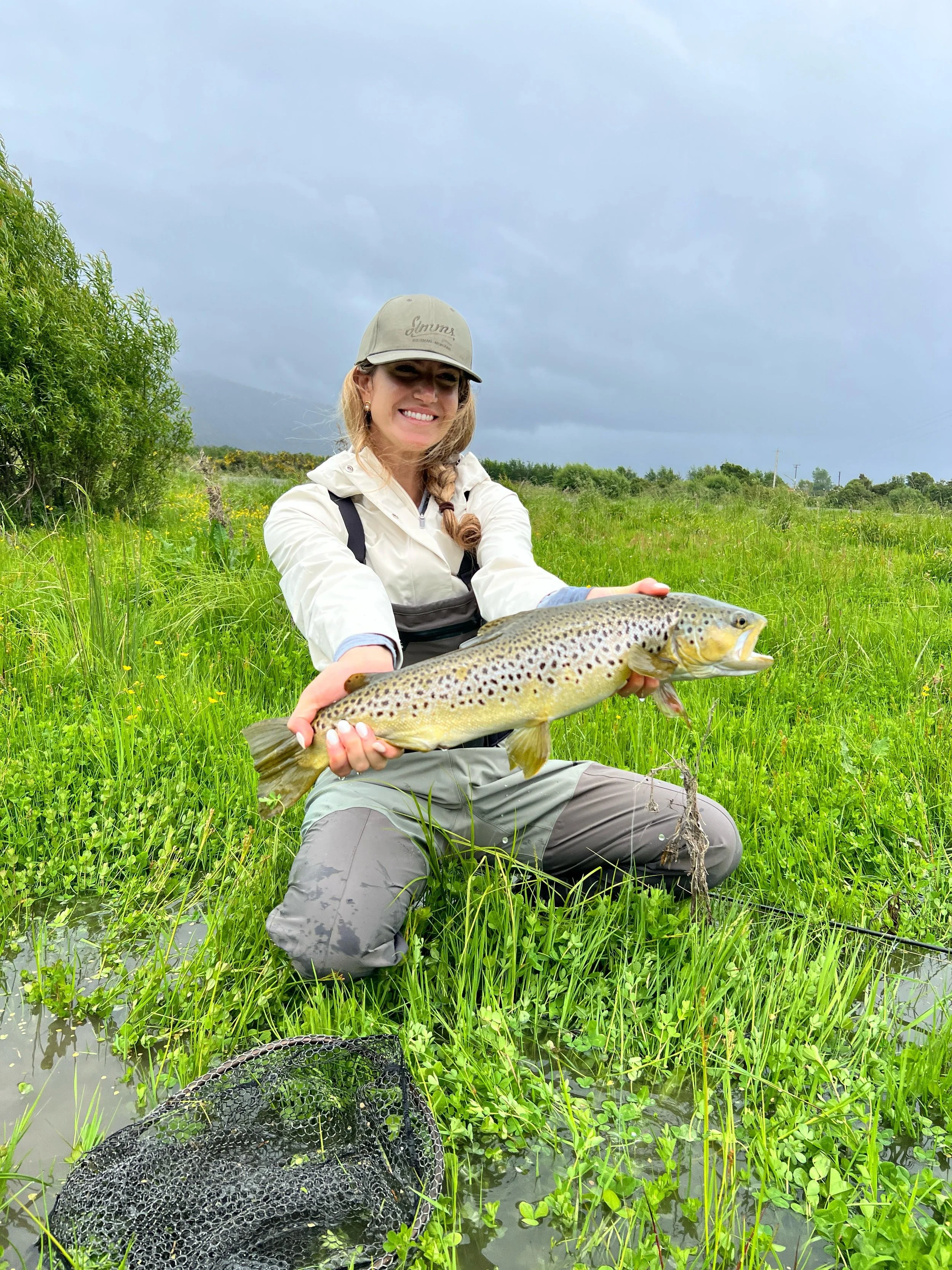 Angler holding a wild brown trout during a guided fly-fishing trip on a West Coast river near Lake Brunner, New Zealand.