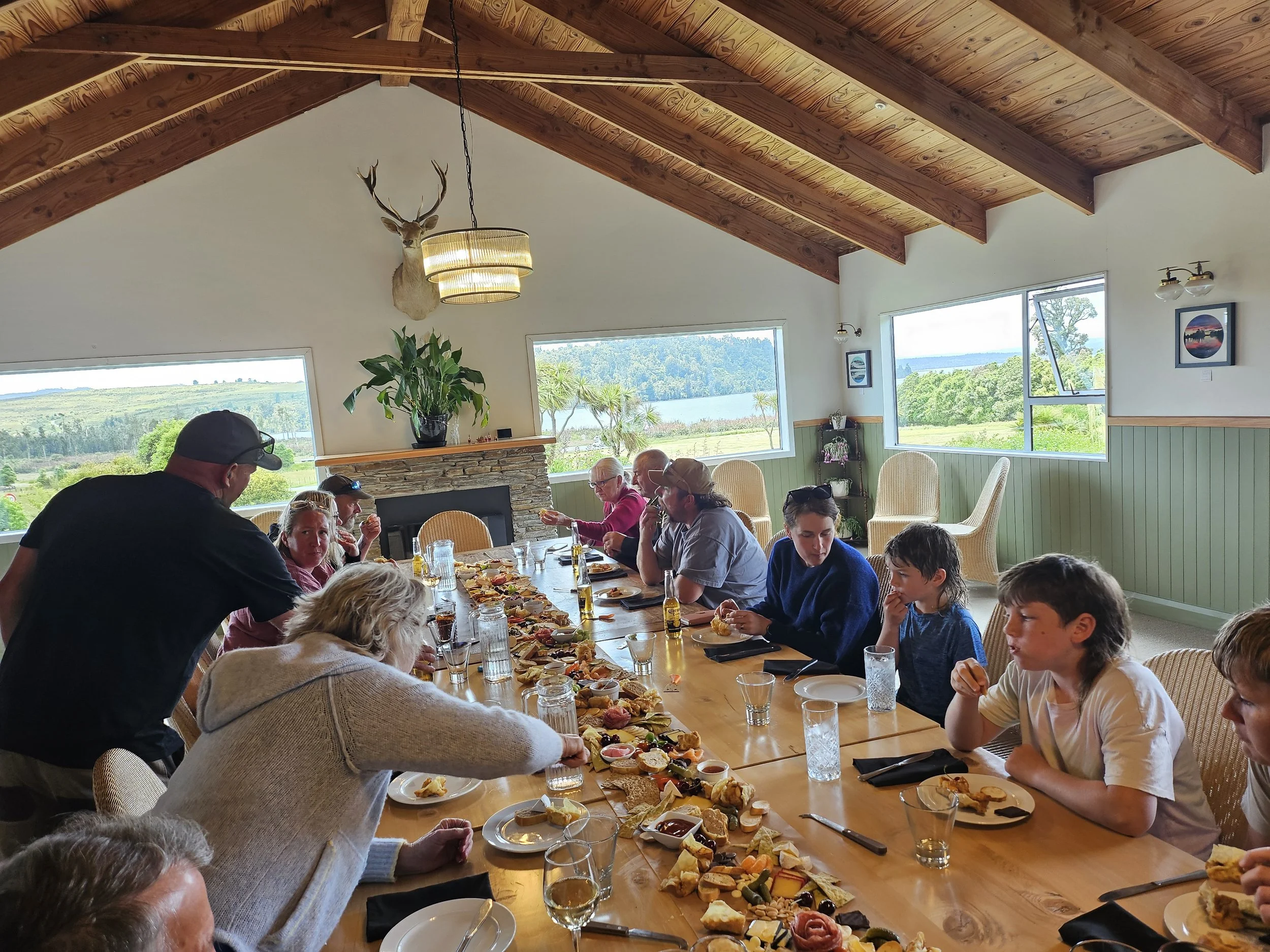 Guests enjoying a hosted shared dining experience at Lake Brunner Eco Lodge on New Zealand’s West Coast. Long-table dining overlooking native wilderness, ideal for exclusive-use group stays, family celebrations, retreats, and hosted eco-lodge.