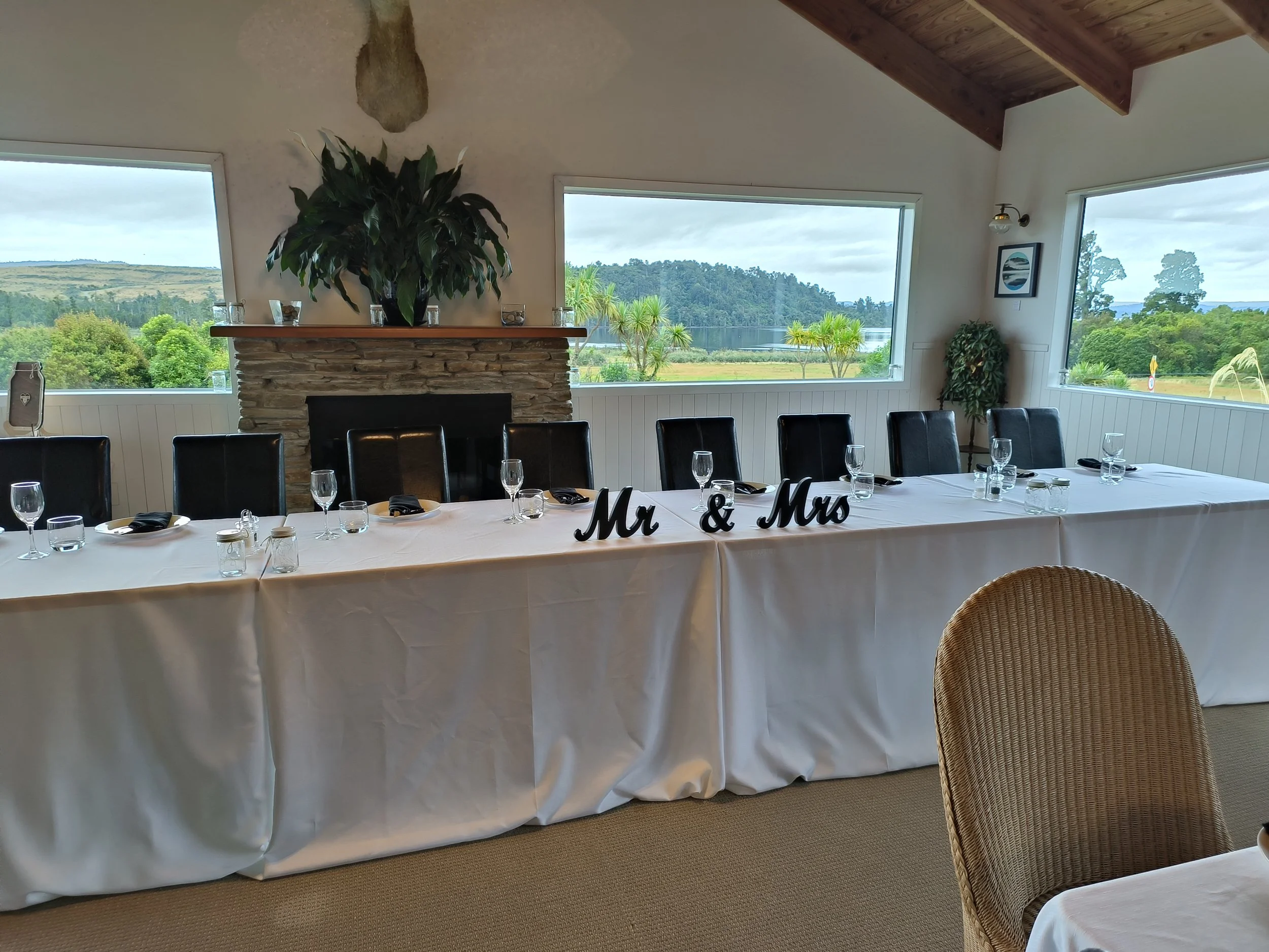 Intimate wedding reception setup at Lake Brunner Eco Lodge featuring a beautifully styled head table with “Mr & Mrs” signage overlooking the New Zealand West Coast landscape. Private luxury lodge venue for micro weddings.