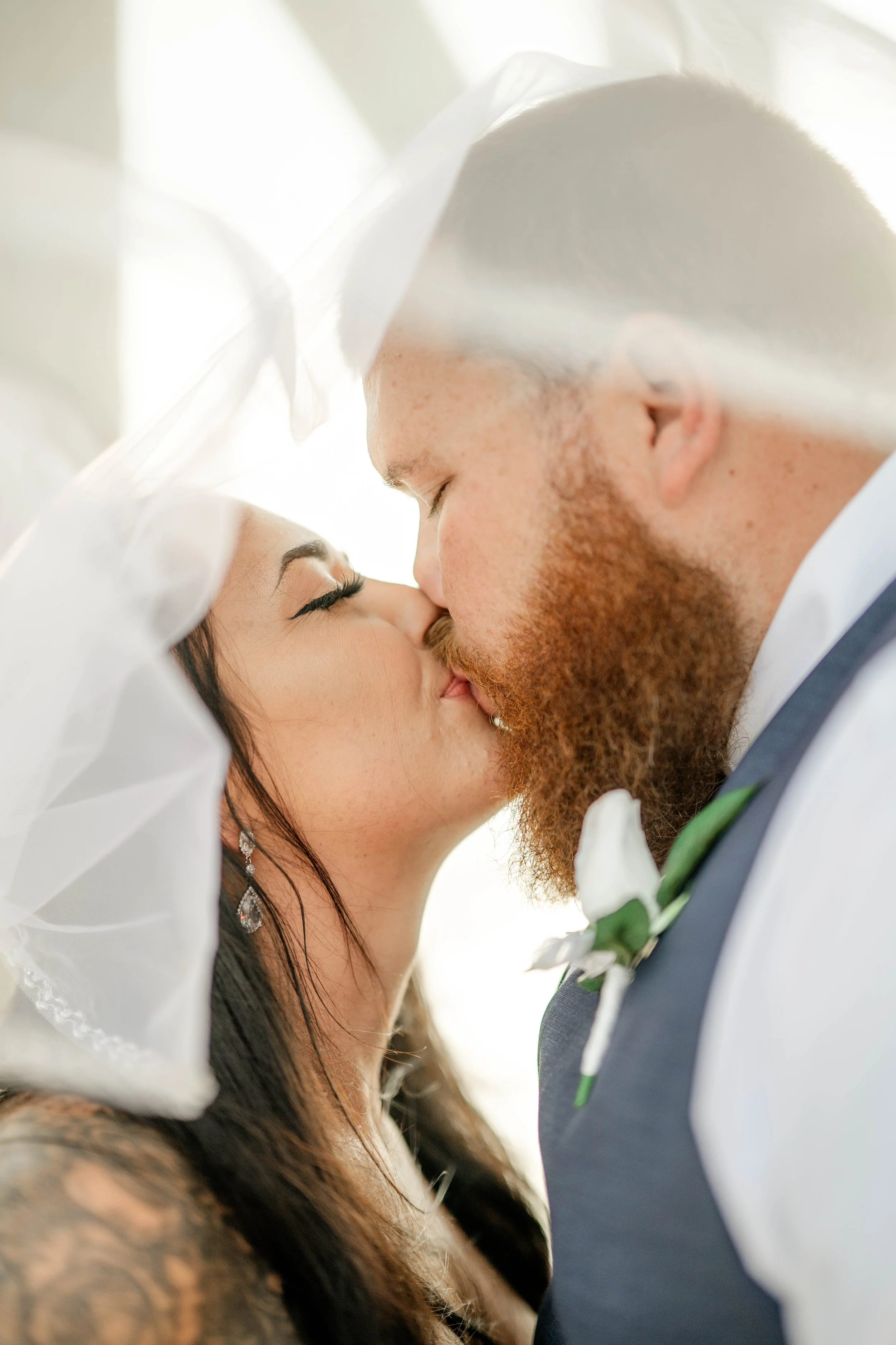A bride and groom kissing under a white veil during their wedding ceremony. St andrews state park weddings, Panama City beach weddings, PCB Photographers, PCB weddings