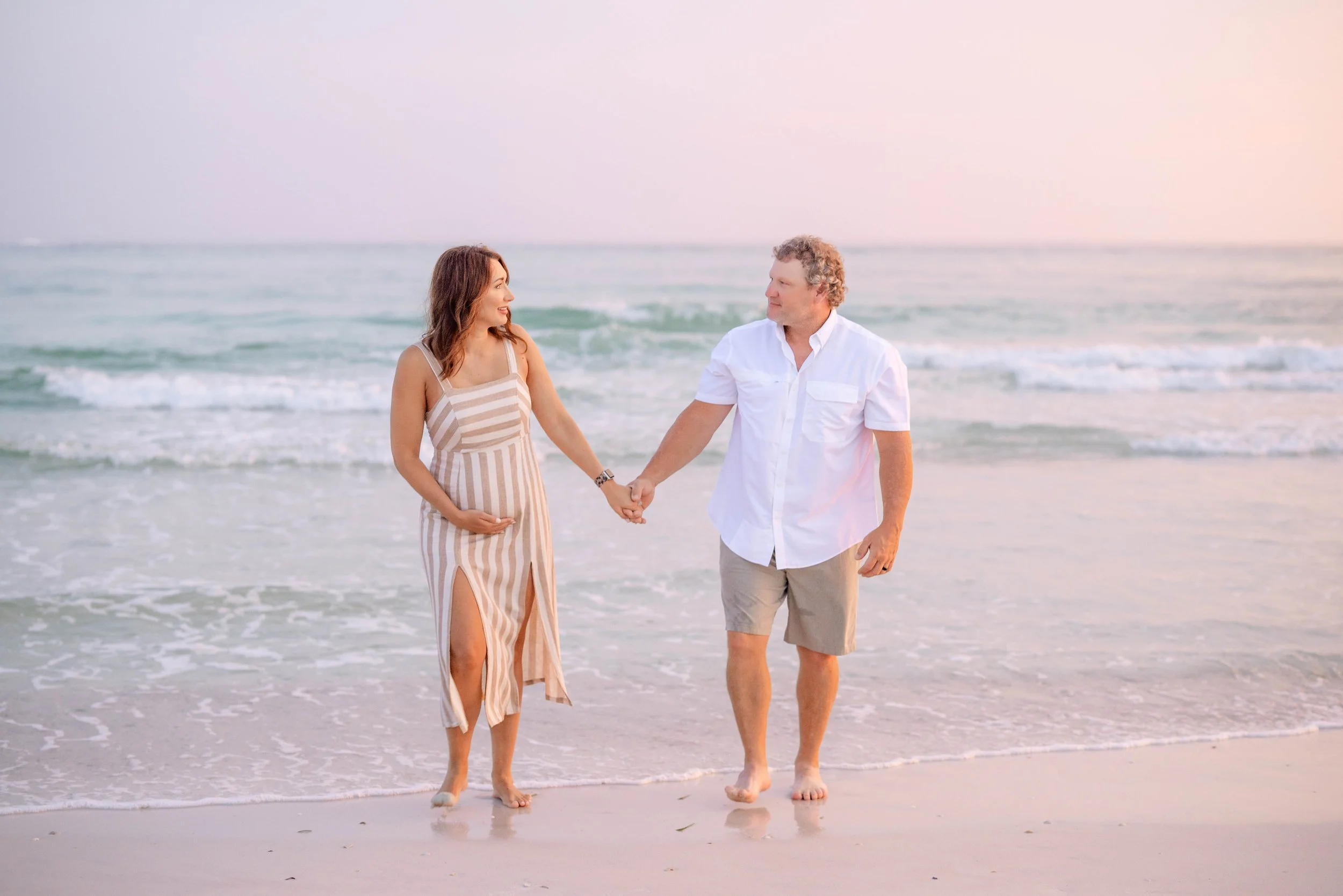 man and woman holding hands on the beach in Panama City beach during a photoshoot.