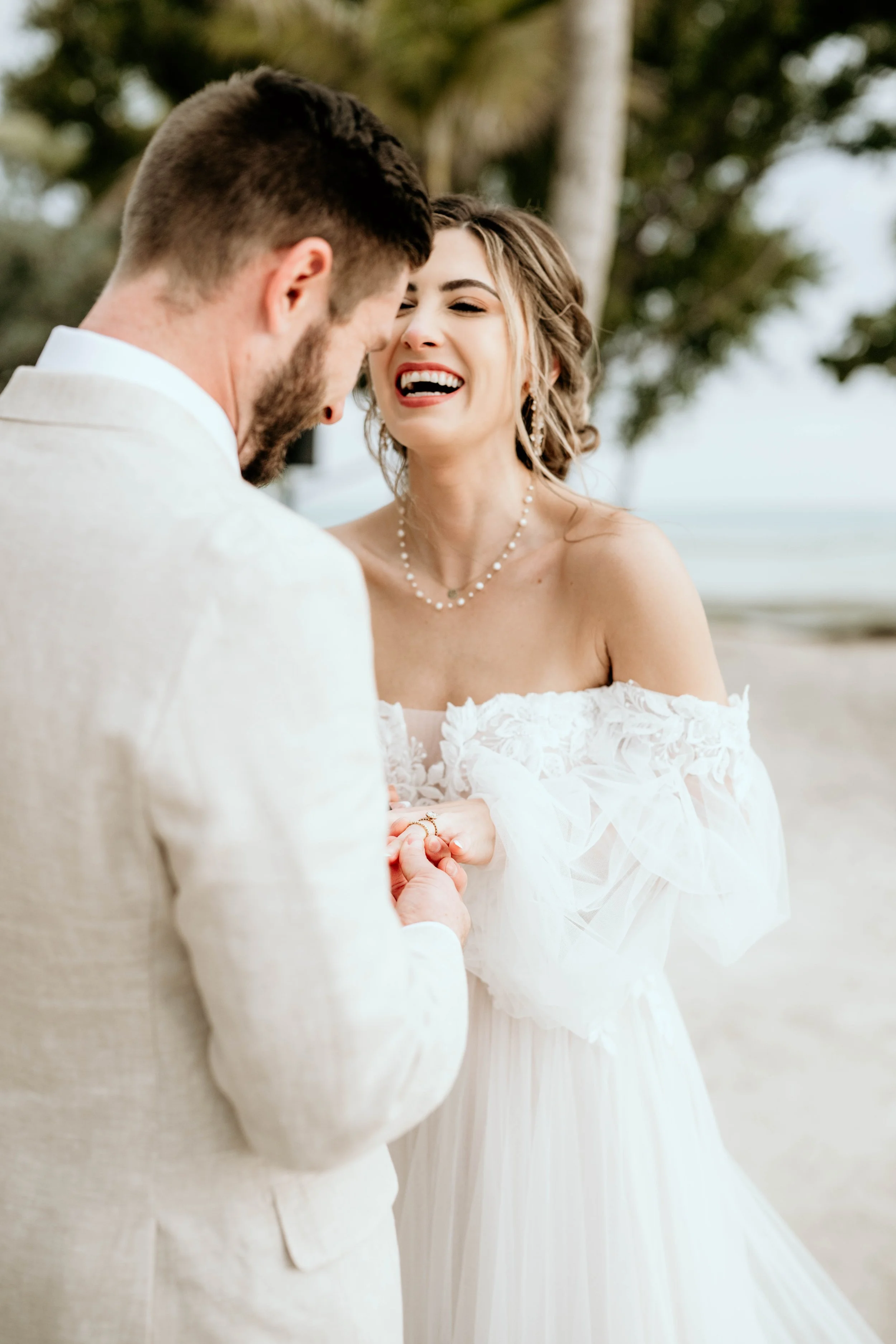 A bride and groom exchanging rings on a beach during their wedding, with palm trees in the background. Panama City beach weddings, PCB Photographers, PCB weddings