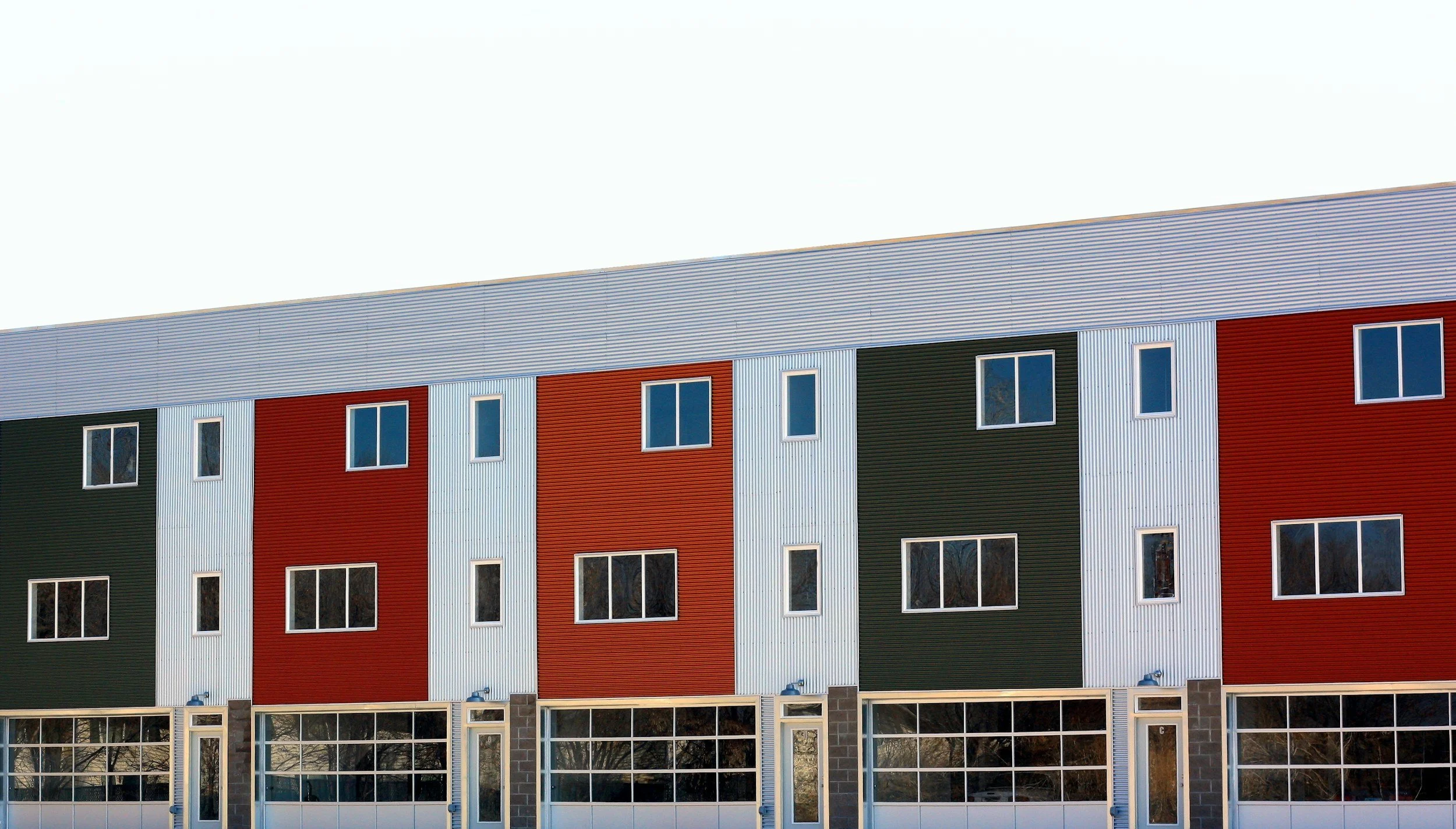 Colorful building with red, green, and white paneling, multiple windows, and a flat roof.
