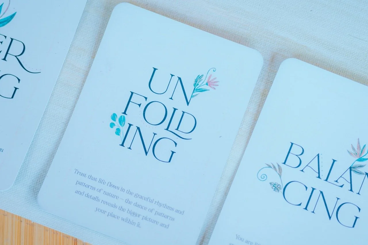 Cards with floral design and uplifting messages, including one that says "Unfolding" and another that says "Balancing".