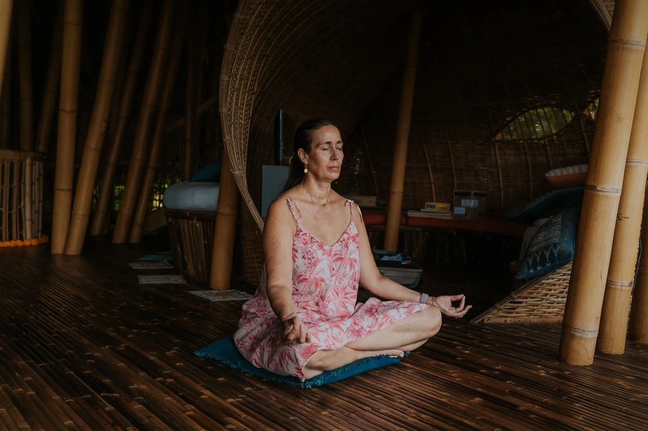 A woman practicing yoga in a bamboo hut with natural lighting.