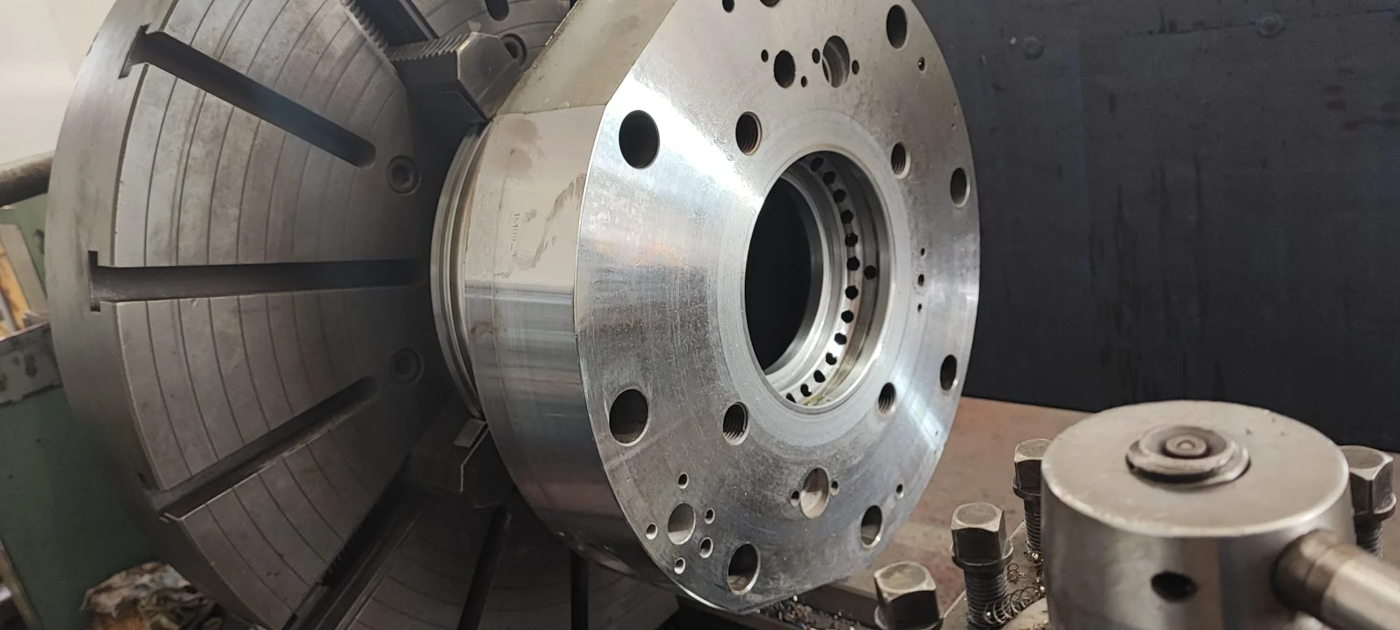 Close-up of a large metal lathe chuck and workpiece in a machining workshop.