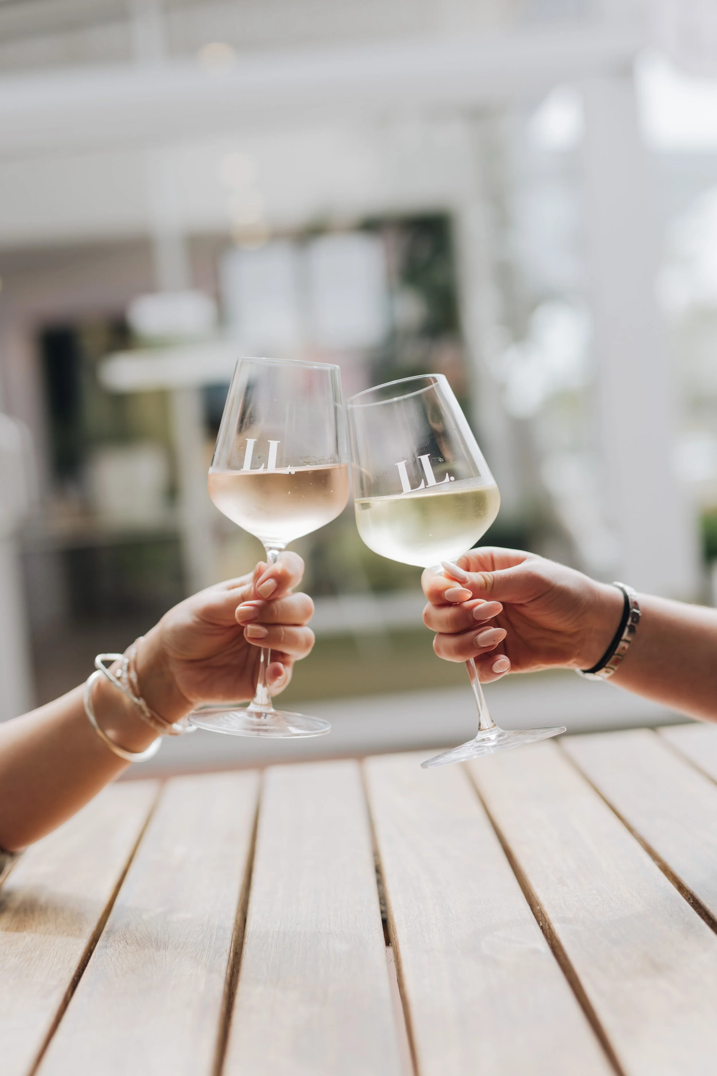 Two people clinking glasses of white wine in a bright, modern setting.