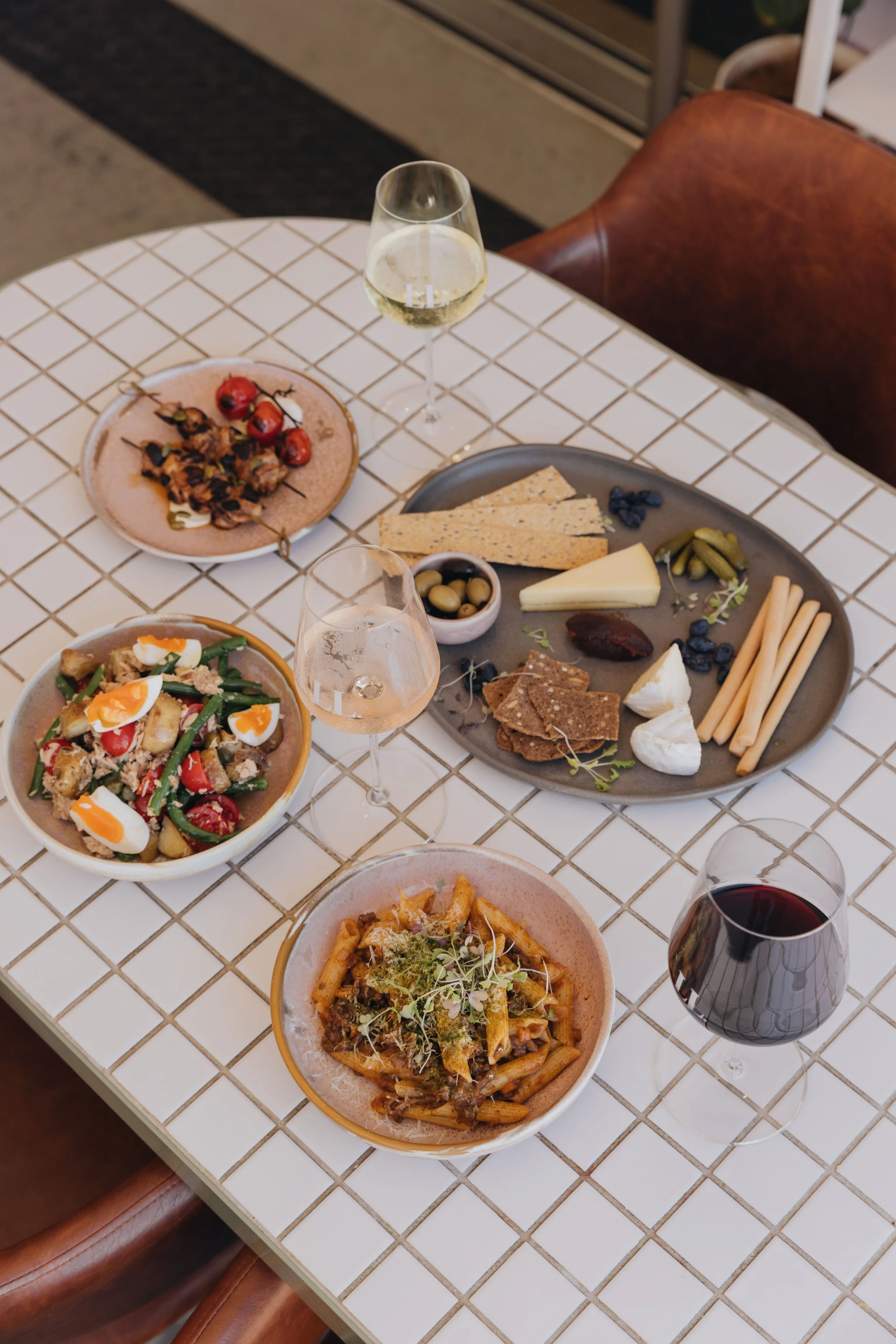 A table with various dishes, glasses of white and red wine, and an assortment of cheeses and snacks