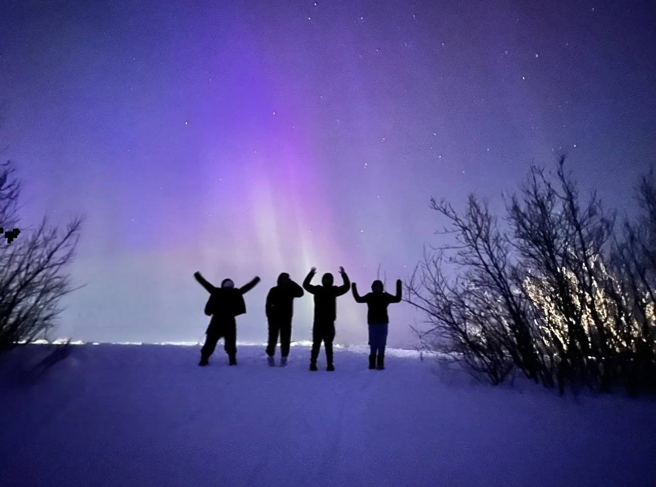 4 learners in the snow in front of purple northern lights