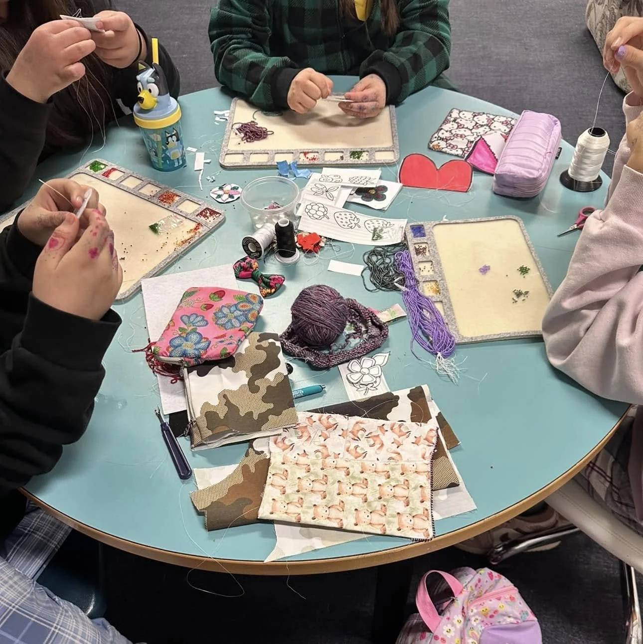 4 learners beading around a circular table