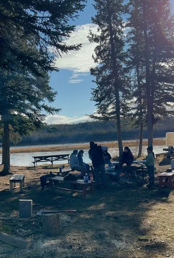 Learners gathered around a firepit in front of the river
