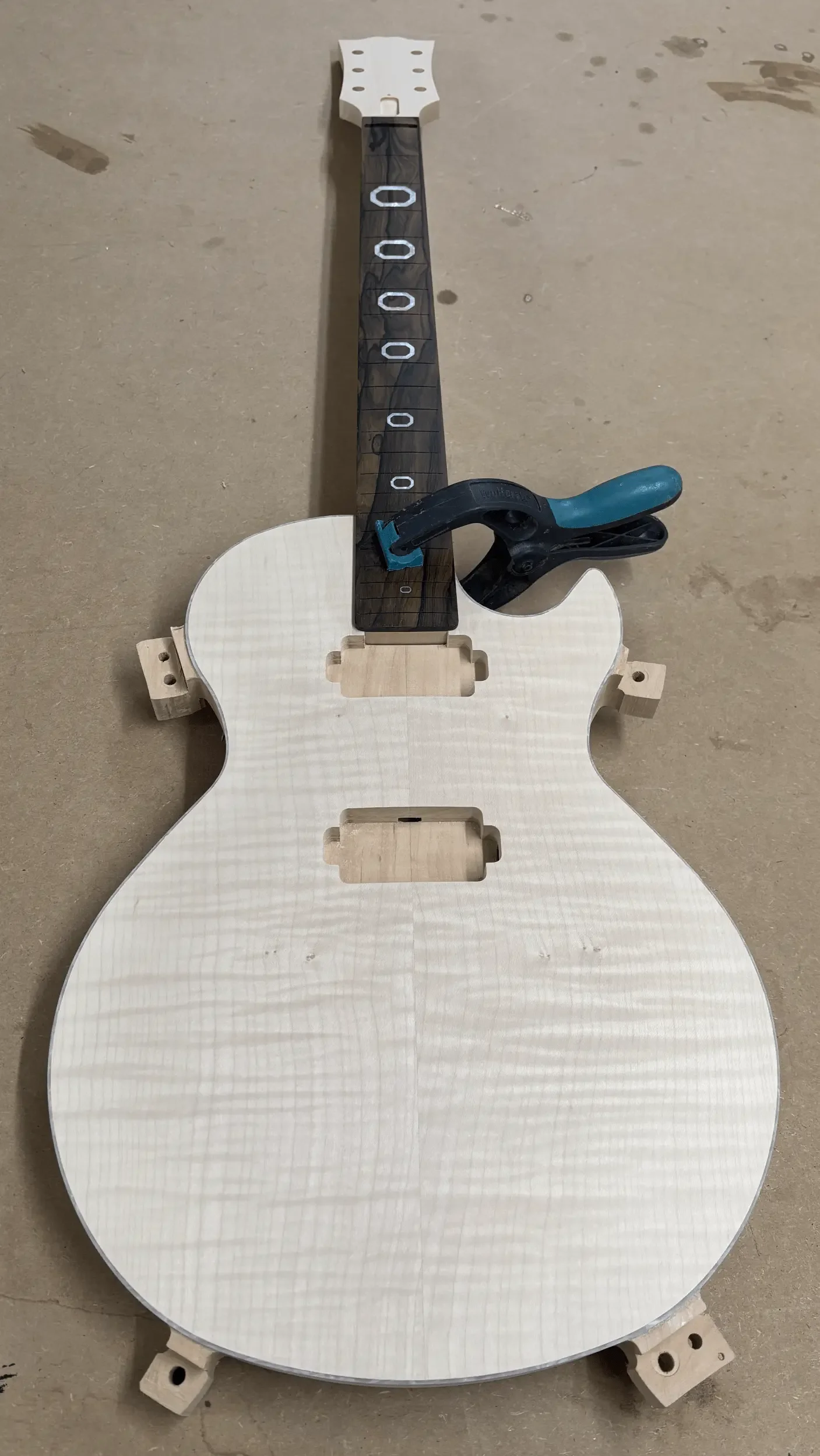 E-Gitarre vor Übergabe. Form ausgefräst, aber noch mit Fräshaltern.