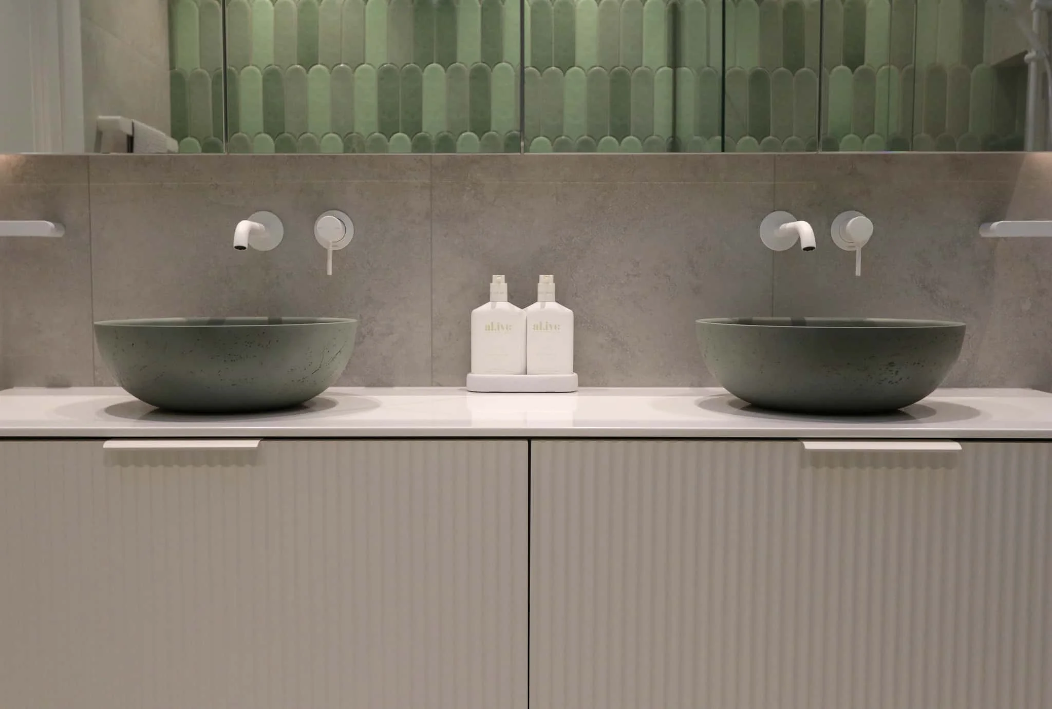 Sage green concrete vessel basin sitting on a fluted white vanity unit