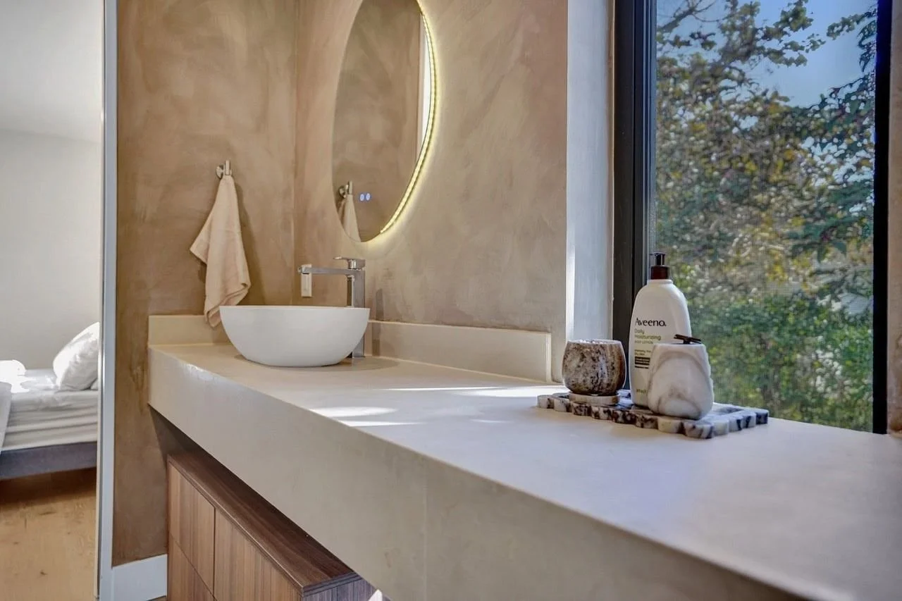Luxury Essendon ensuite featuring a fluted stone feature wall, organic backlit mirror, and concrete vanity