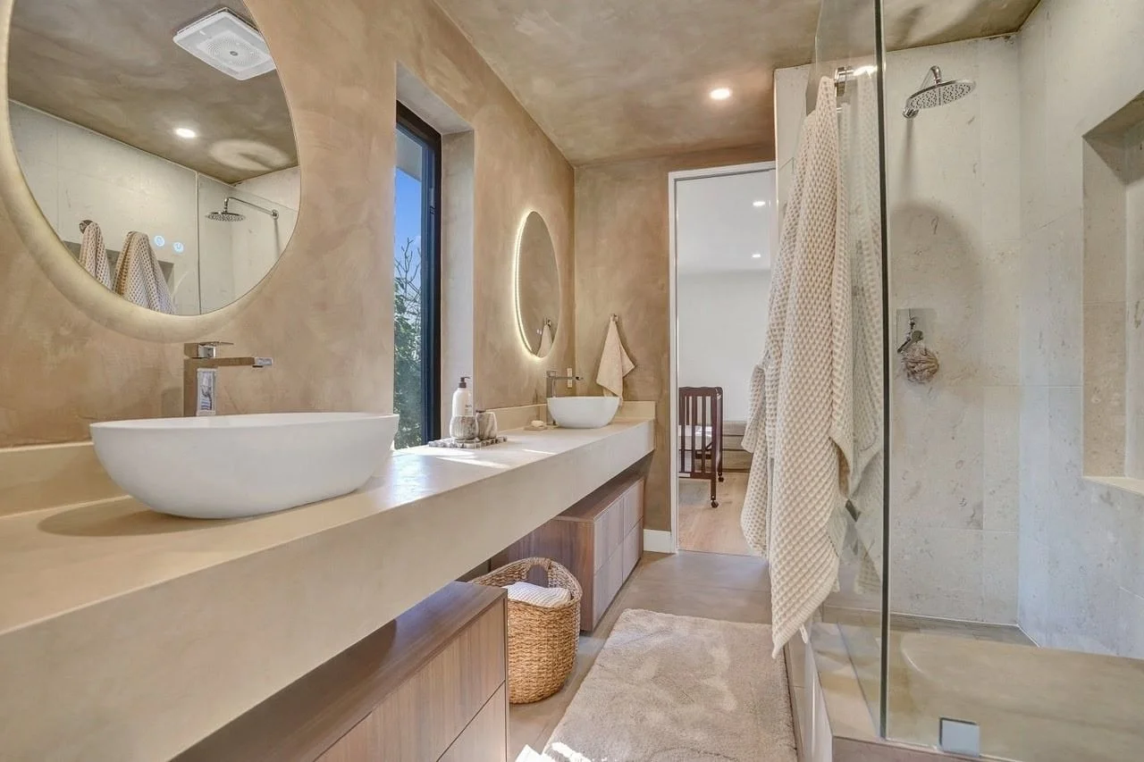 Spacious master en suite with double concrete vanities, round mirrors, and glass walk-in shower in Essendon
