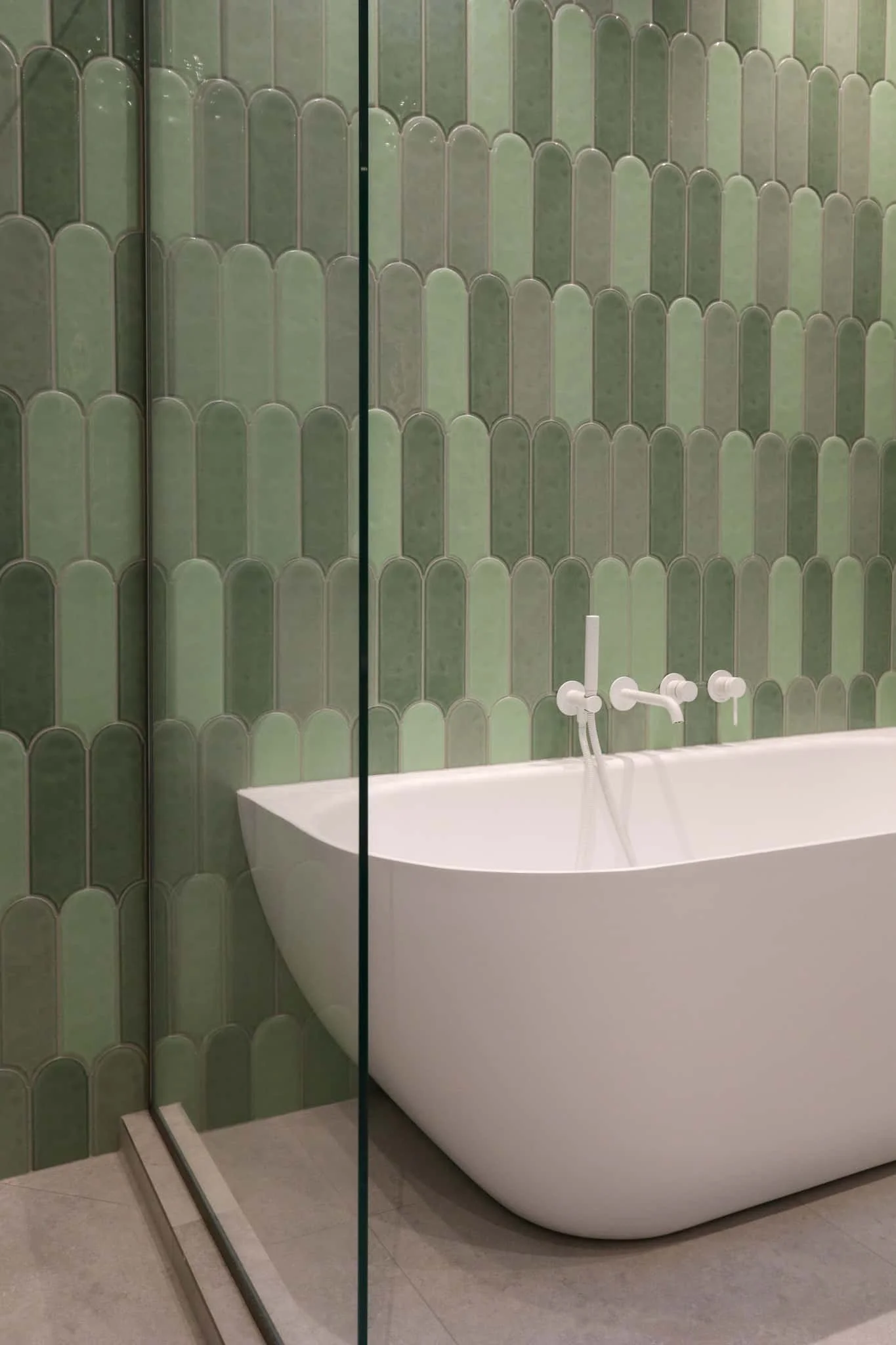Sage green arching kit-kat feature wall tiles with matte white shower tapware in Strathmore renovation