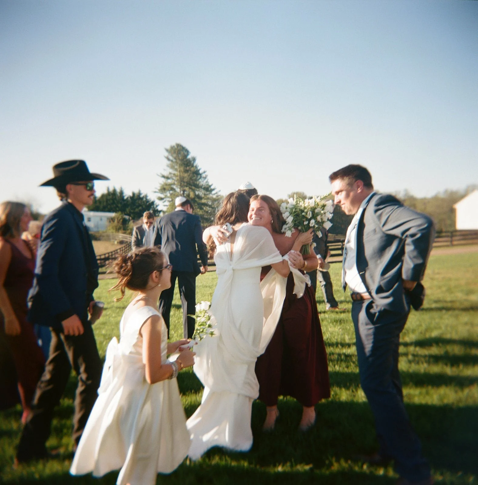 People hugging and celebrating outdoors at a wedding.