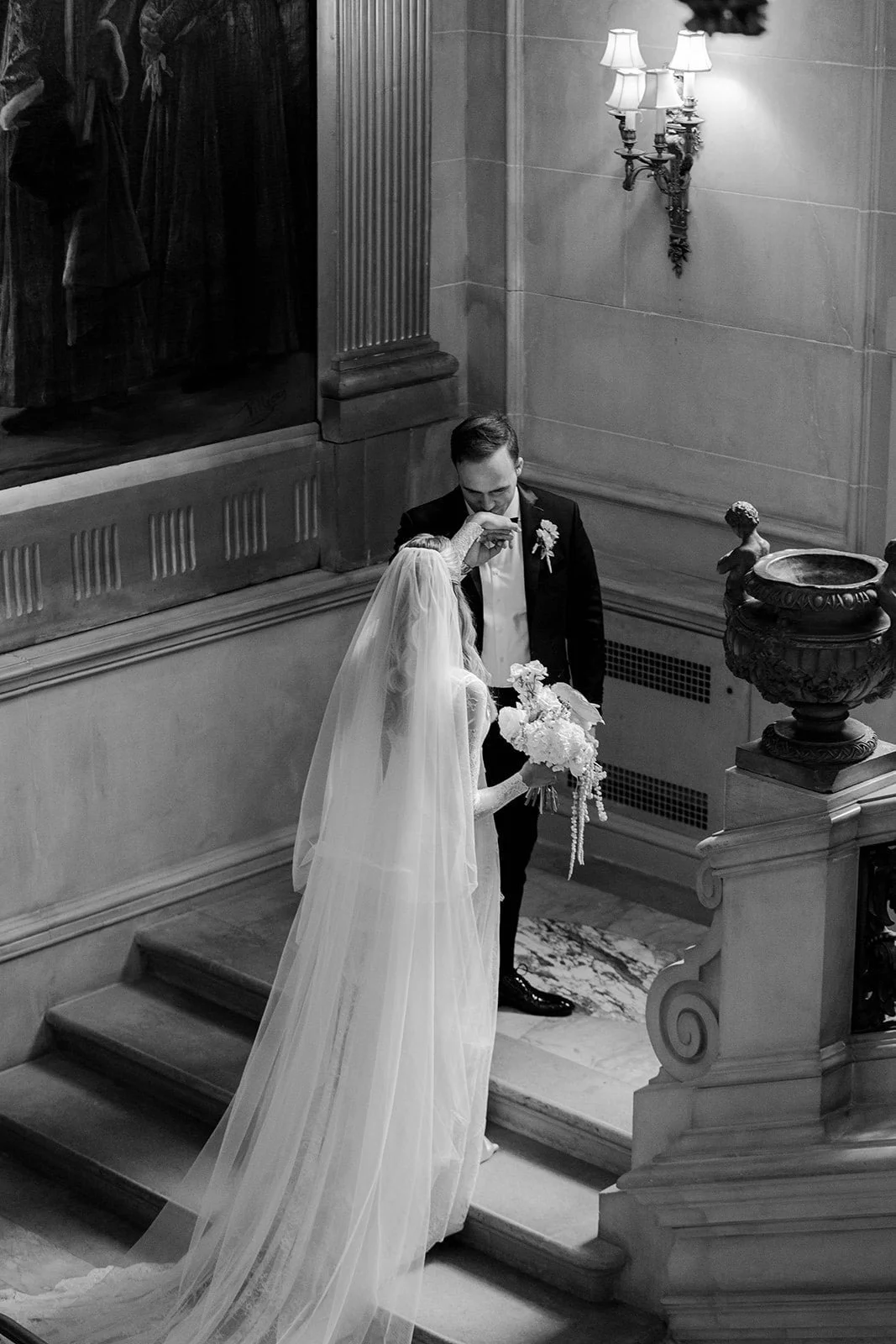 A black-and-white photo of a bride and groom on the stairs during their wedding ceremony at The Larz Anderson House in Washington DC