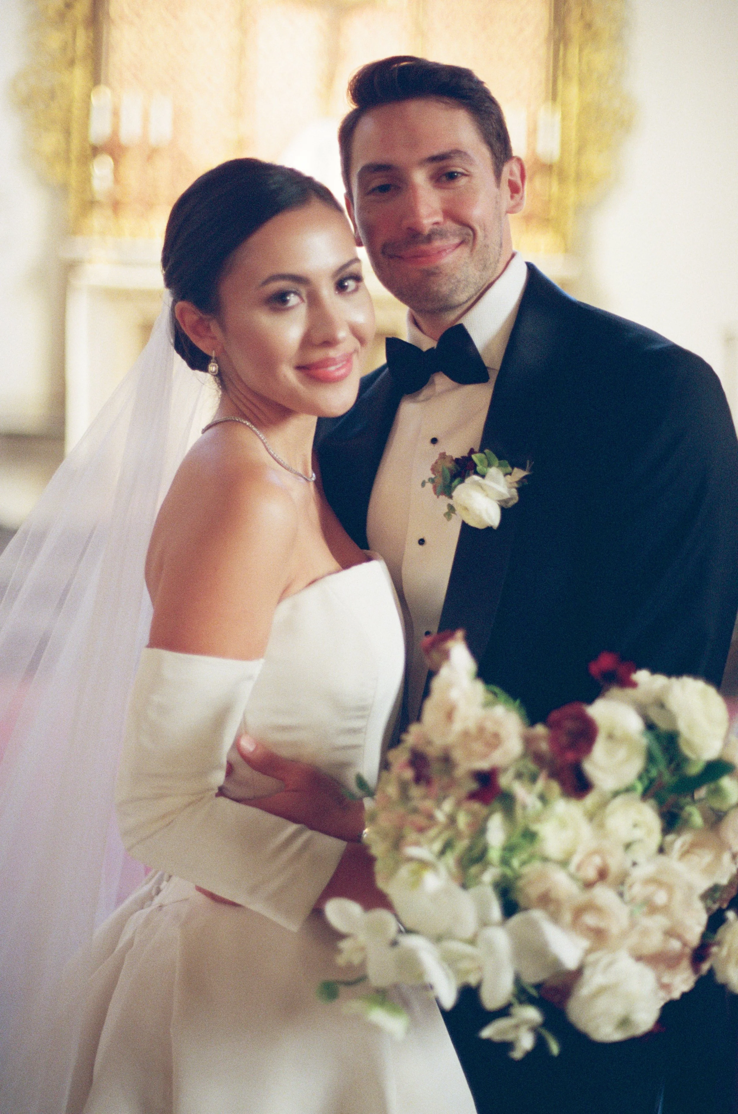 A bride and groom smiling and posing together at their wedding, with the bride holding a bouquet of flowers at the St. Regis Hotel in Washington DC