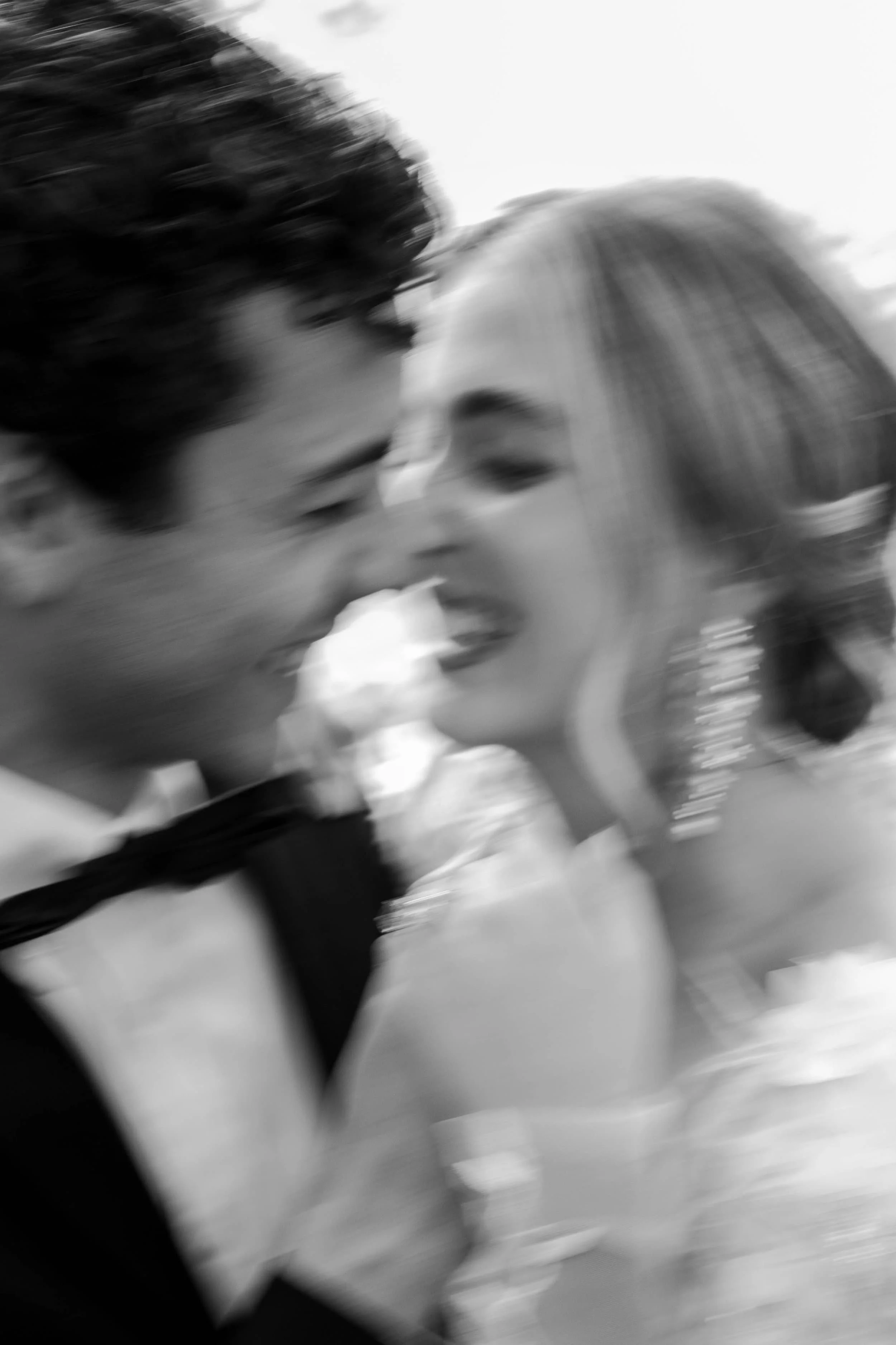Blurred black-and-white photo of a couple smiling and leaning close to each other, possibly at a special event.