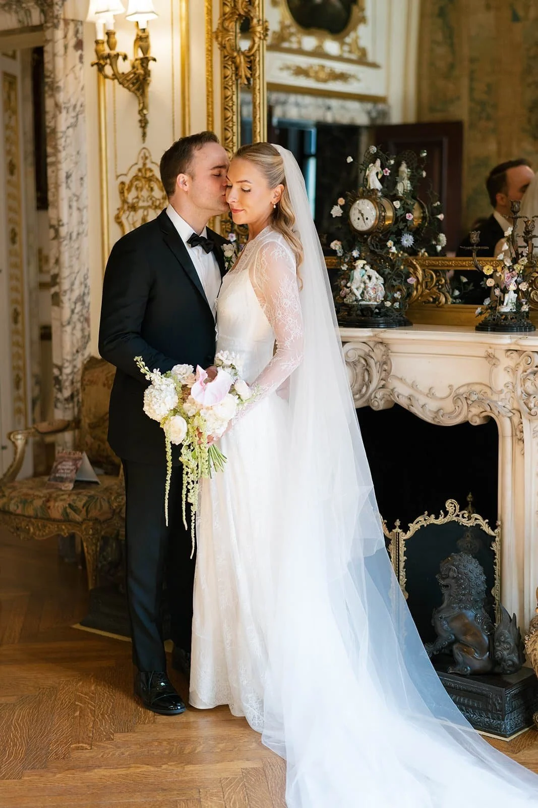 A bride and groom in formal wedding attire standing close to each other in an elegant, ornate room at The Larz Anderson House in Washington DC.