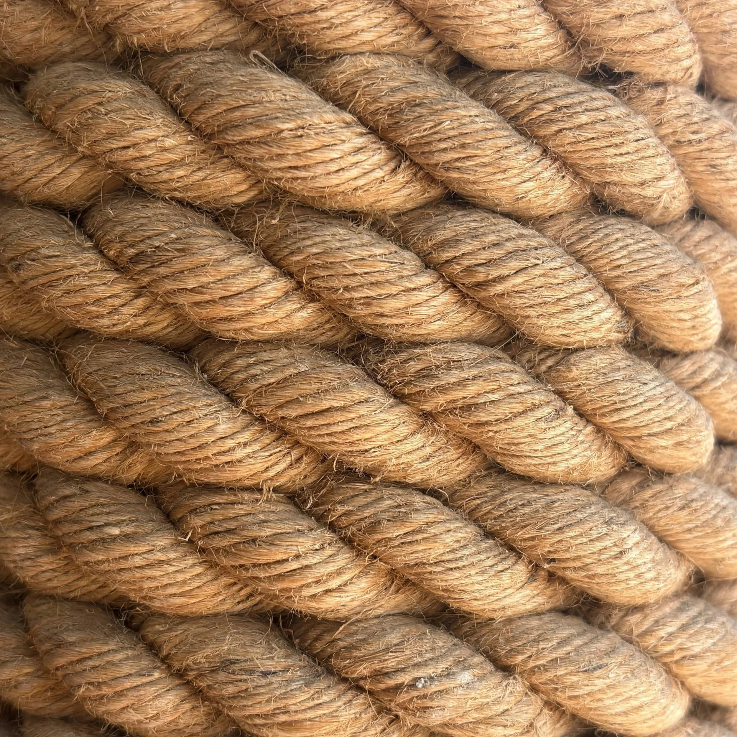 Close-up of coiled natural jute rope with rough texture and frayed fibers.