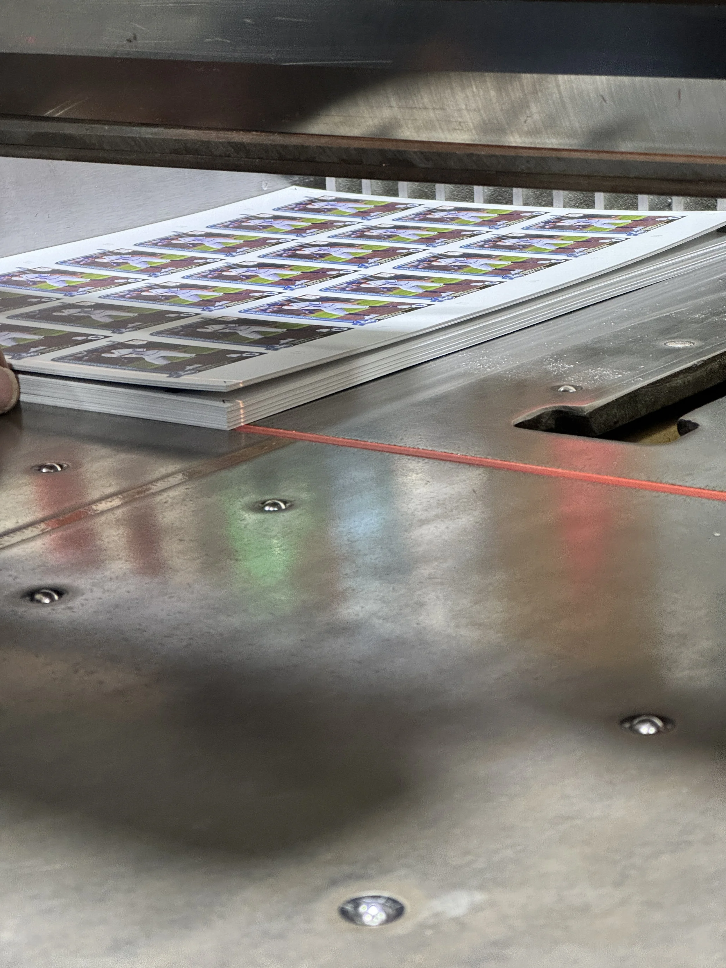 Stack of printed sports cards on a metal worktable.