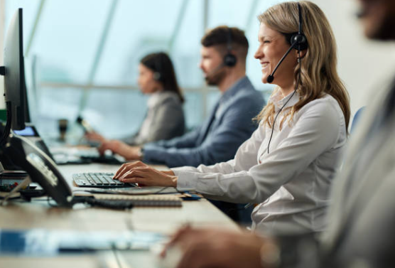 Customer service representatives working at their desks in an office, wearing headsets.