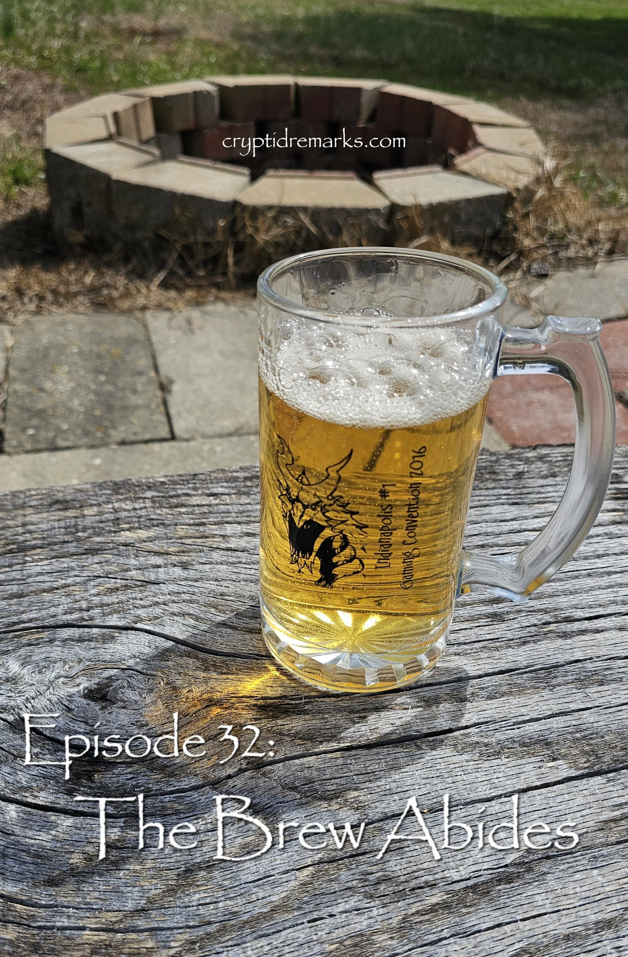 A glass mug of beer on a table in front of a stone firepit.