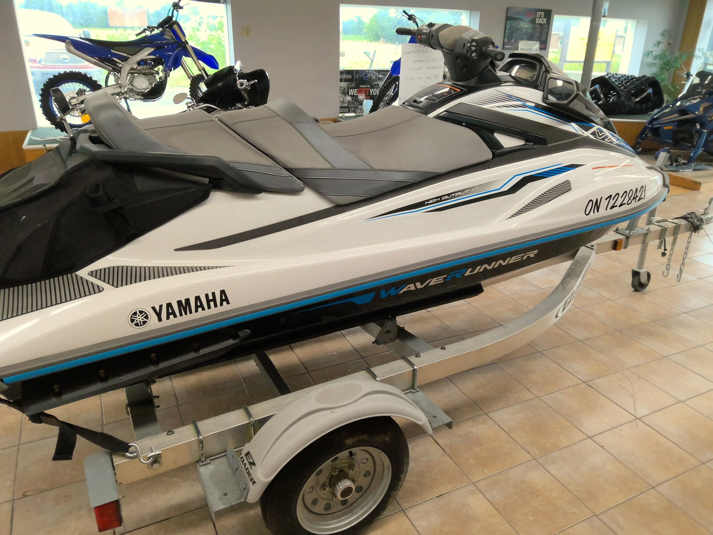 A Yamaha wave runner personal watercraft on a trailer inside a showroom with motorcycle bikes in the background.