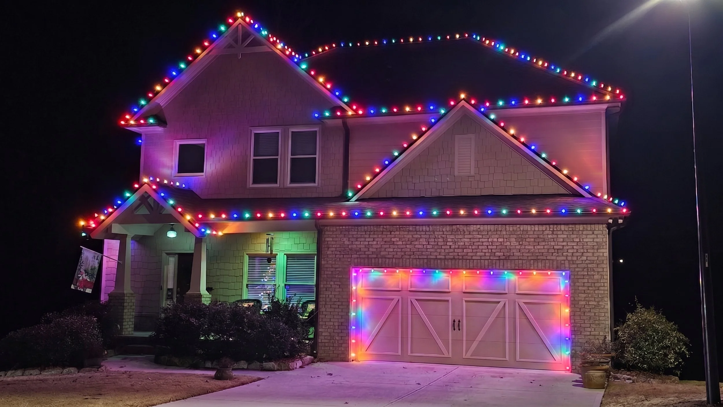 Custom-fit multicolor Christmas lights outlining roof and ridgelines on Dallas GA home