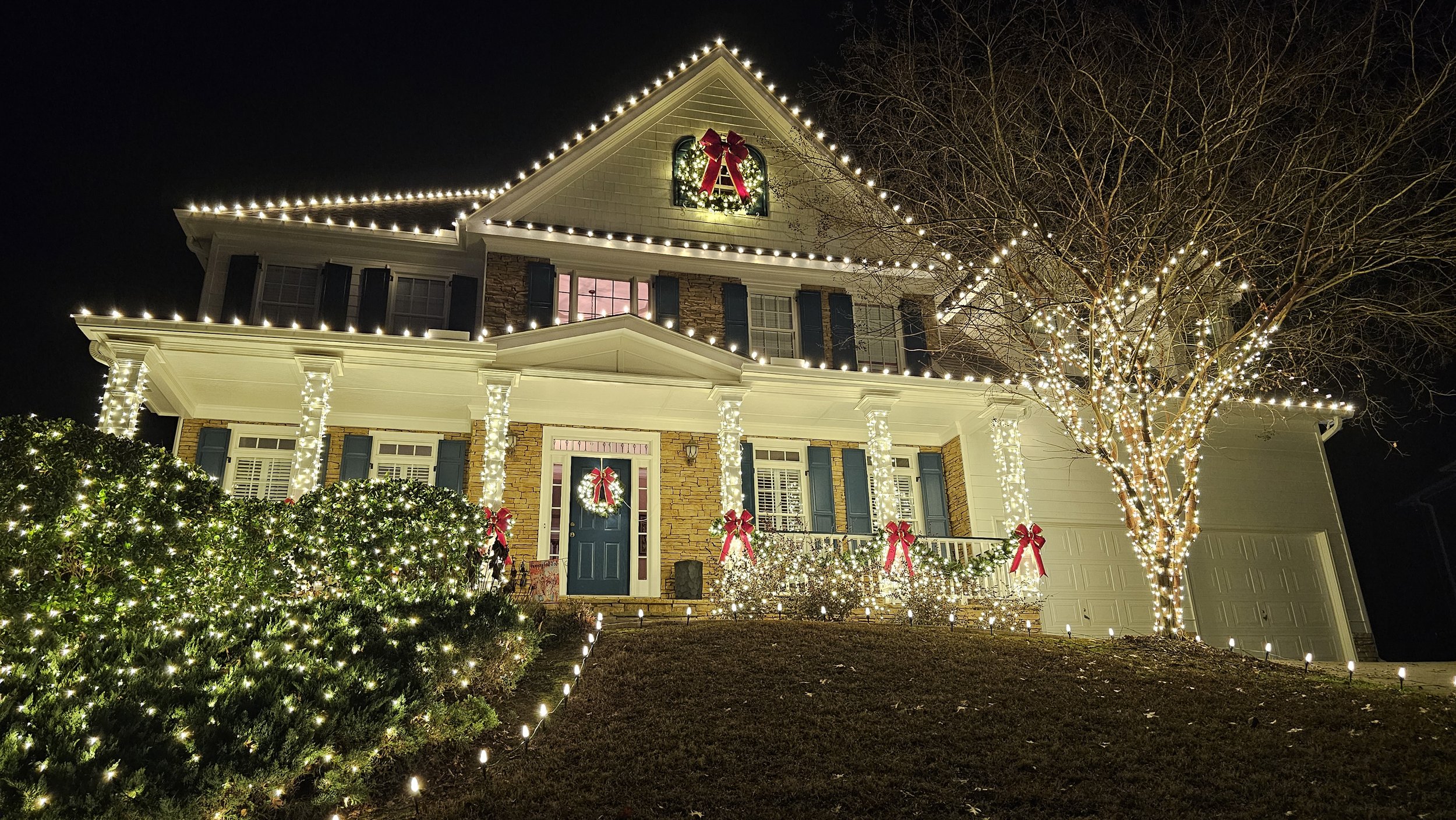 Warm white residential Christmas light installation Brookstone HOA Acworth GA roofline wreaths trees bushes pathway lighting columns