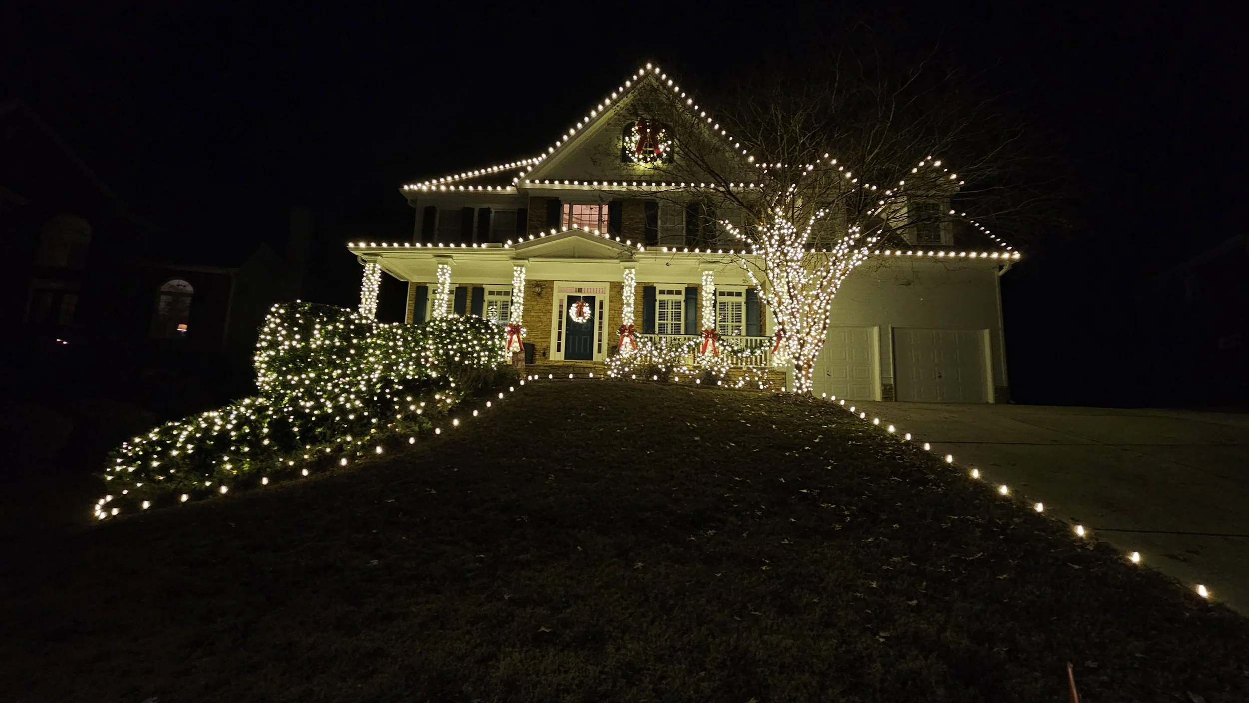 Full property Christmas light installation with roofline trees shrubs and pathways in Brookstone Acworth