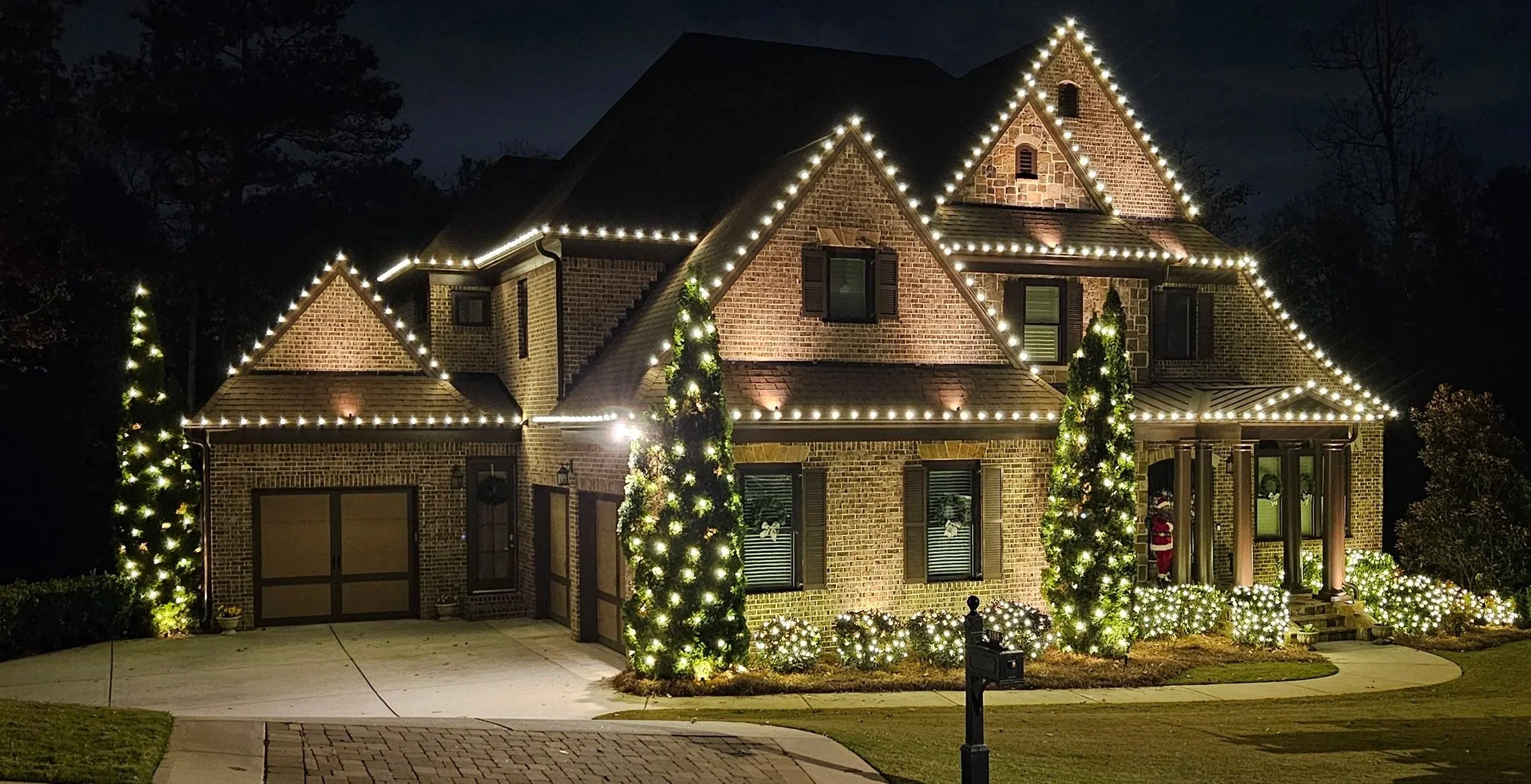 Clean warm white Christmas light installation featuring roofline C9 evergreens and bush wraps in Mableton GA