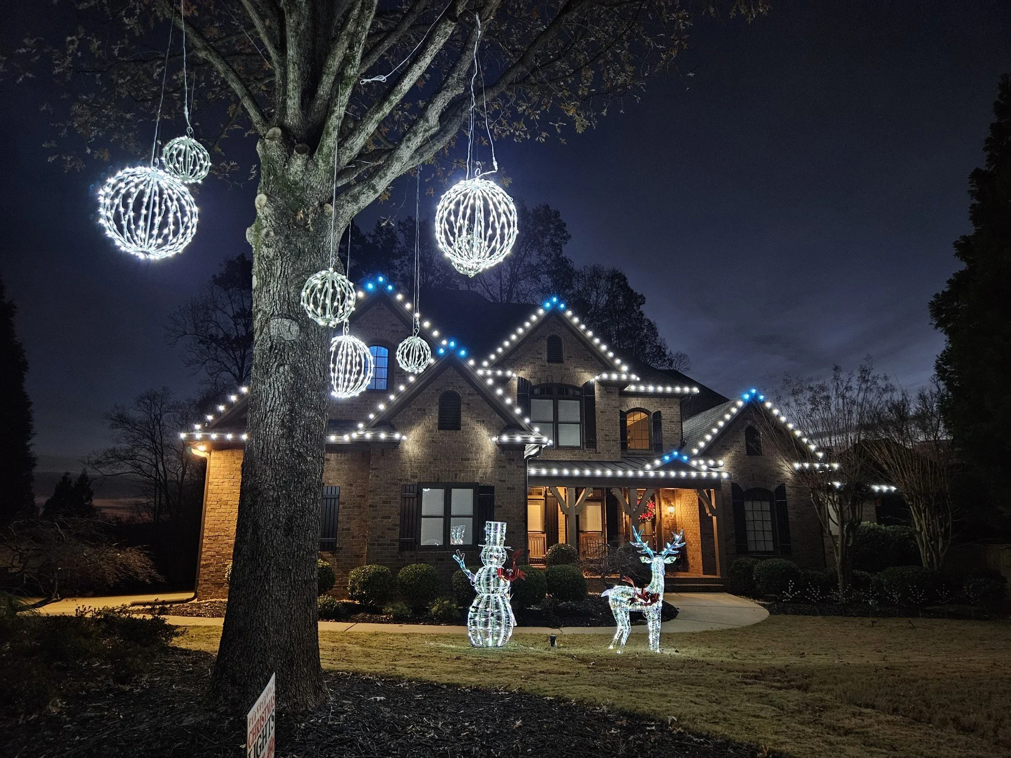 Custom cool white and aqua roofline lights with iridescent lawn ornaments 
