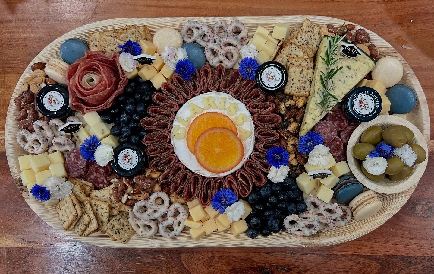 Custom &quot;CLARISSA&quot; Blue Accent Graduation Large Charcuterie Board 💙🎓🥳
&bull;
Palm Leaf Board ~ @tialeafdinnerware 
&bull;
#charcuterie #charcuterieboard #charcuteriebar #graduation #gradparty #birthdaycharcuterie #edibleflower #cheeselove