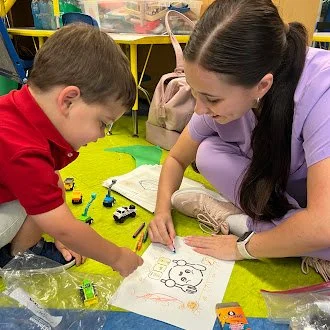 McKenzi with her client in a speech therapy session coloring one of the Playful Paths Speech Therapy Thanksgiving Coloring Book pages
