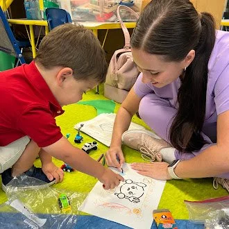 McKenzi with her client in a speech therapy session coloring one of the Playful Paths Speech Therapy Thanksgiving Coloring Book pages more