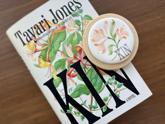 The novel KIN by Tayari Jones pictured with a hand-painted cookie that honors the design of the book cover.