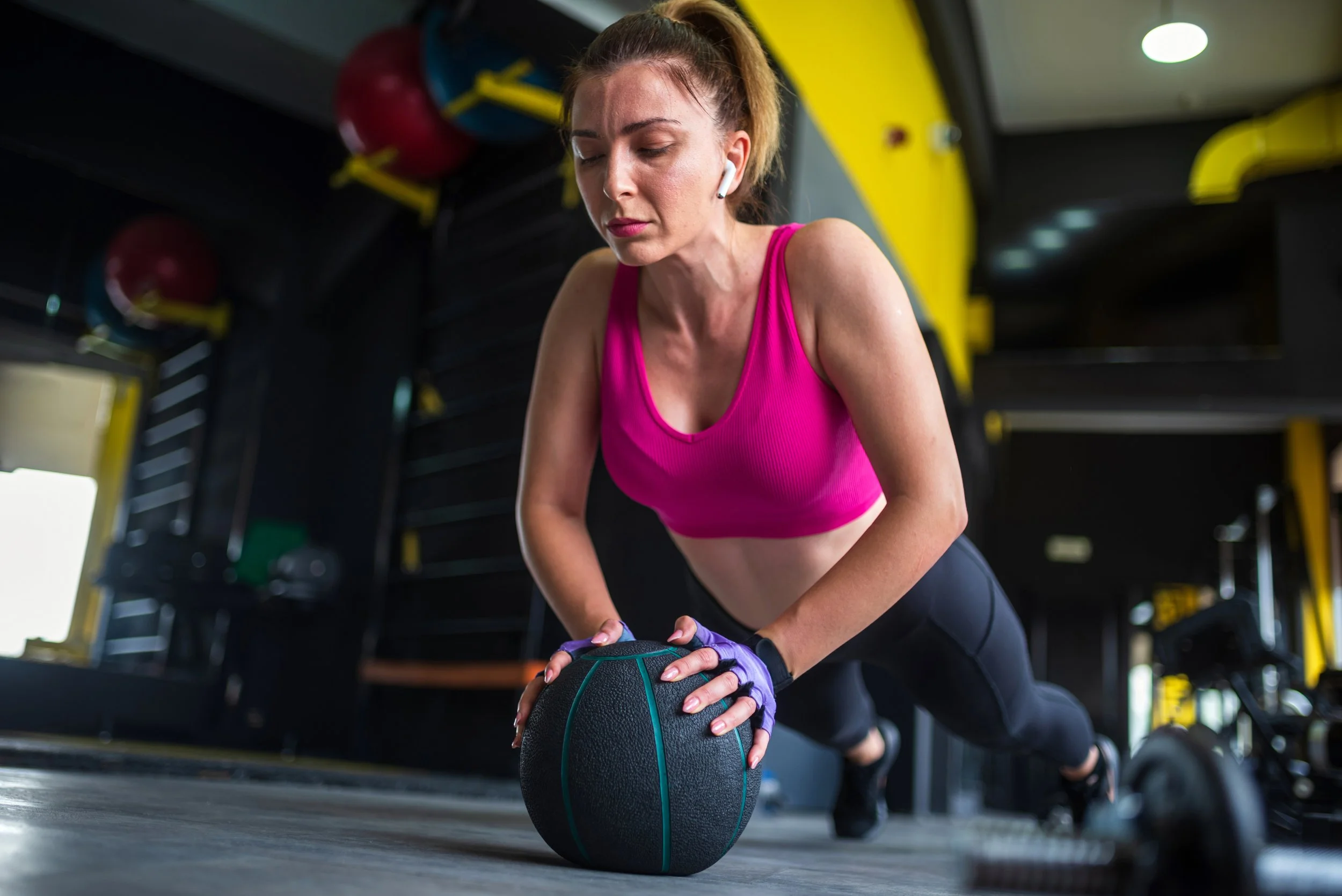 Woman doing a pushup using a weighted medicine ball the size of a basketball.