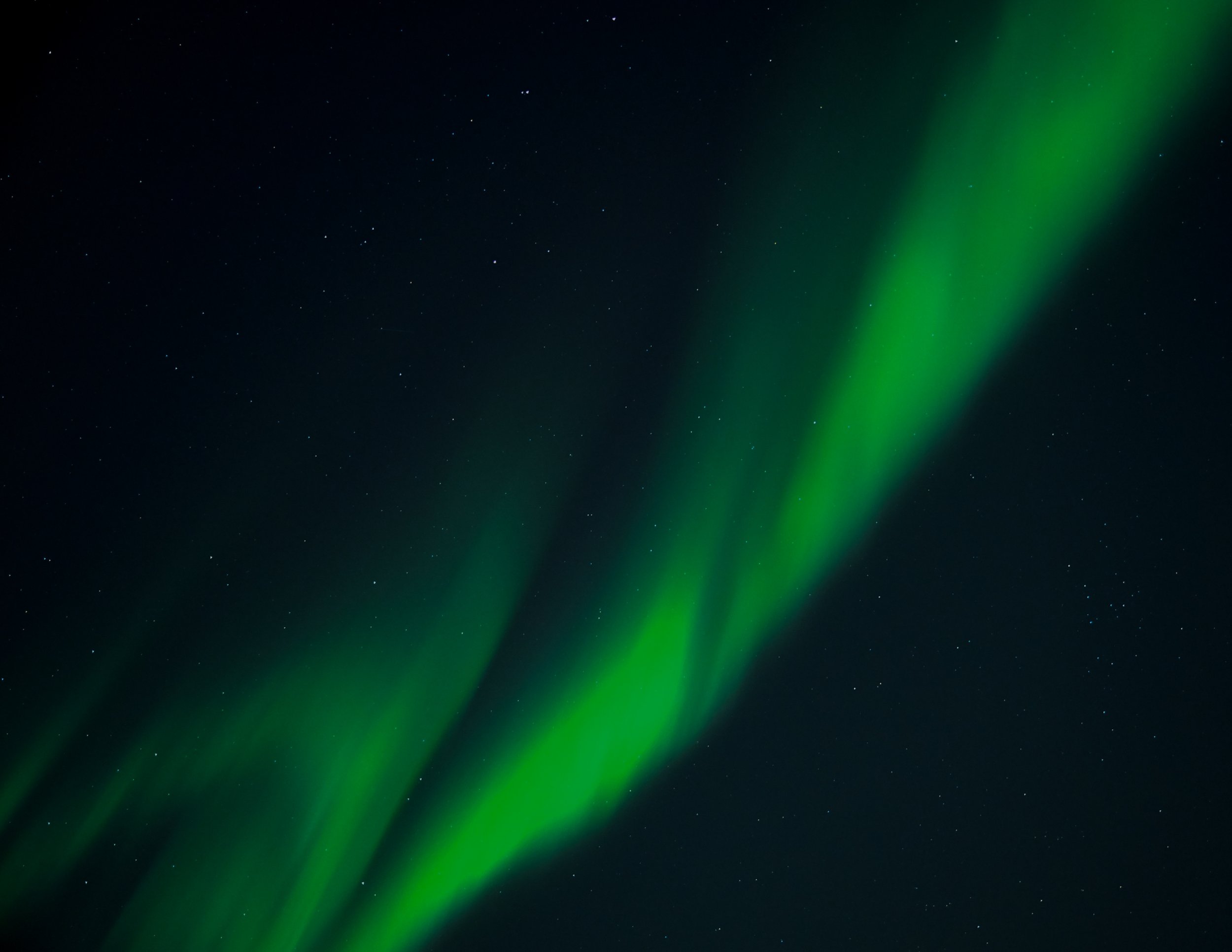 Night sky with stars and a green aurora borealis.