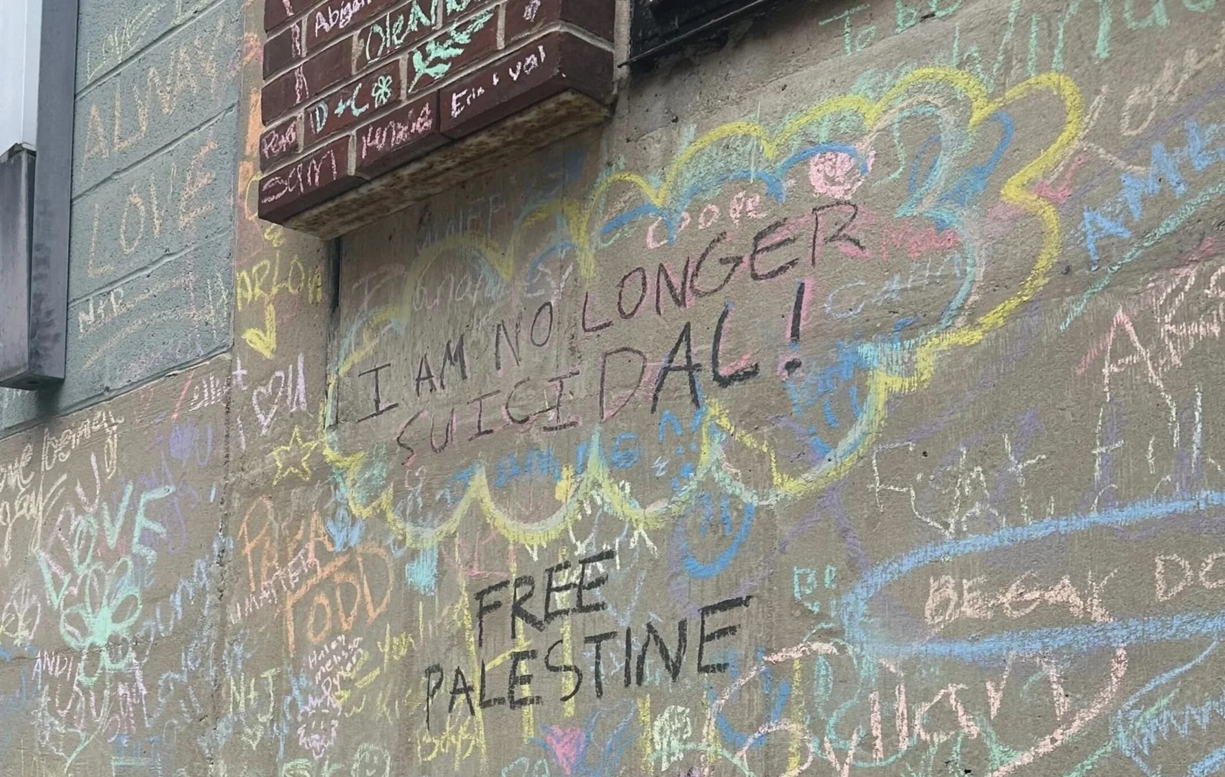 Chalk text on wall at the 2025 Pride Festival that says "I am no longer suicidal"