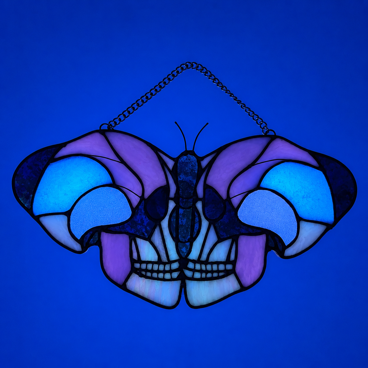 Skull moth stained glass in pink, iridescent black, and white