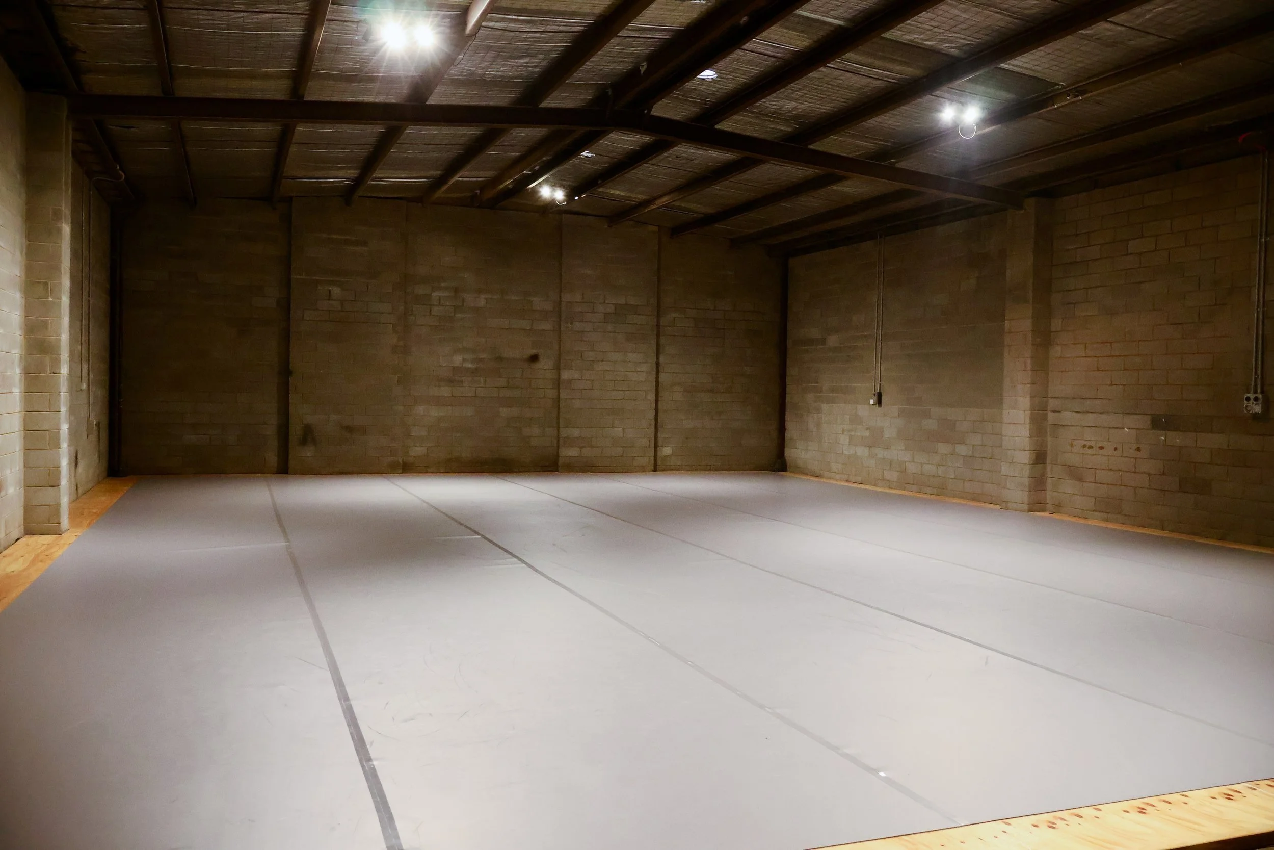 An empty warehouse with a Tarkett dance floor with dim lights and cosy feel