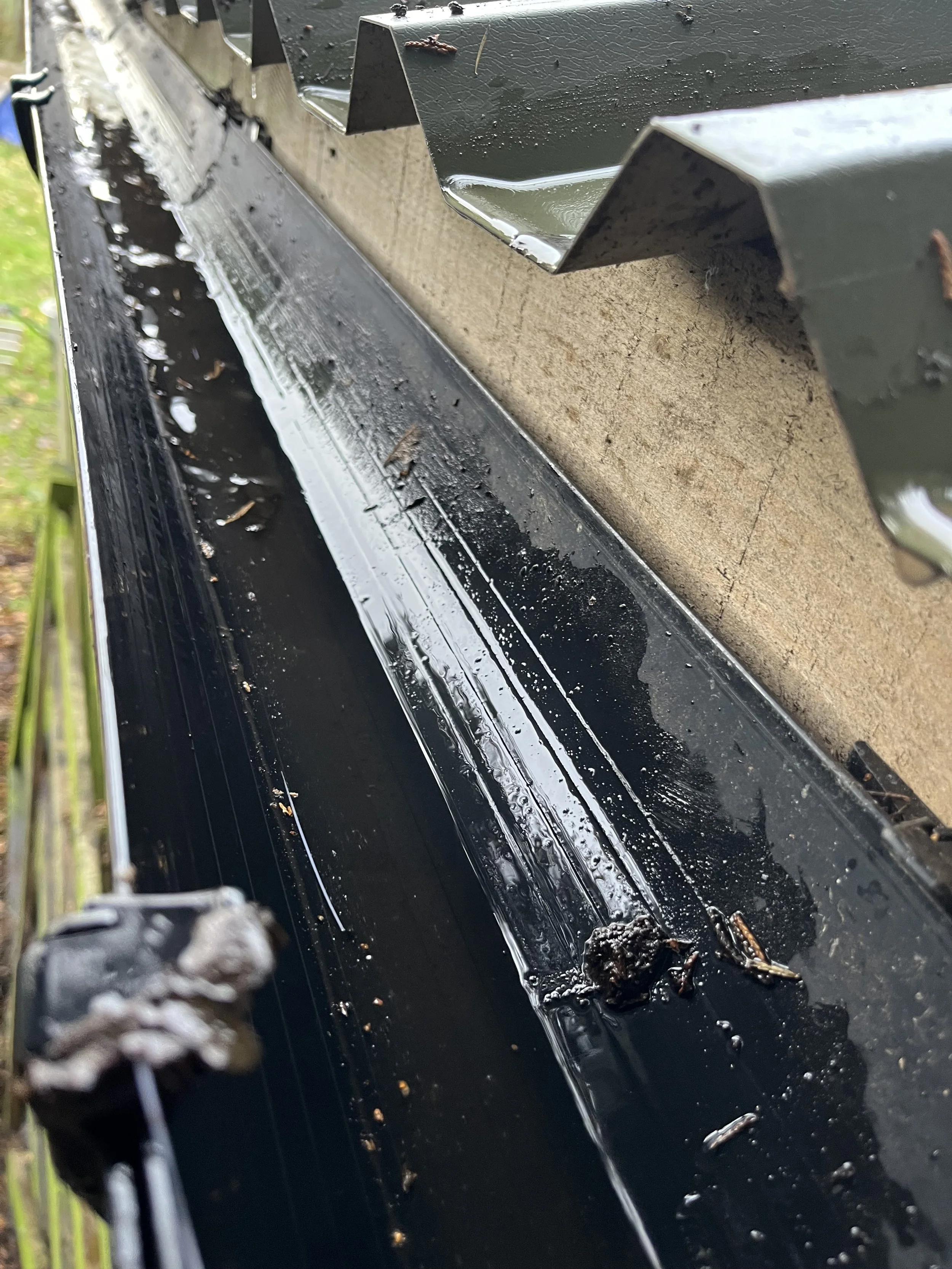 Close-up of a leaf guard gutter system with water and debris accumulated inside.